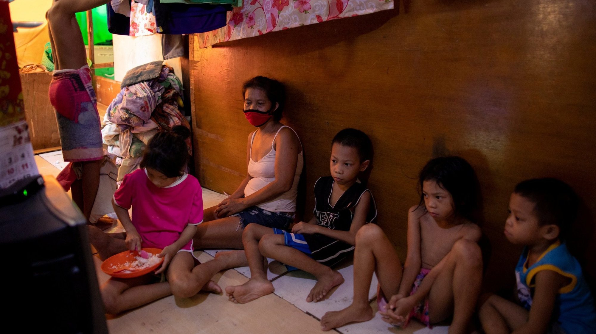 A mother wearing a protective mask looks on while her children share a plate of rice in their home in Manila, Philippines, May 25, 2020, during the COVID-19 pandemic. The head of the Philippine bishops' conference has appealed to Catholics to give food to the poor so that they do not go hungry during a near-total lockdown in Manila Aug. 6-20, 2021. (CNS photo/Eloisa Lopez, Reuters)