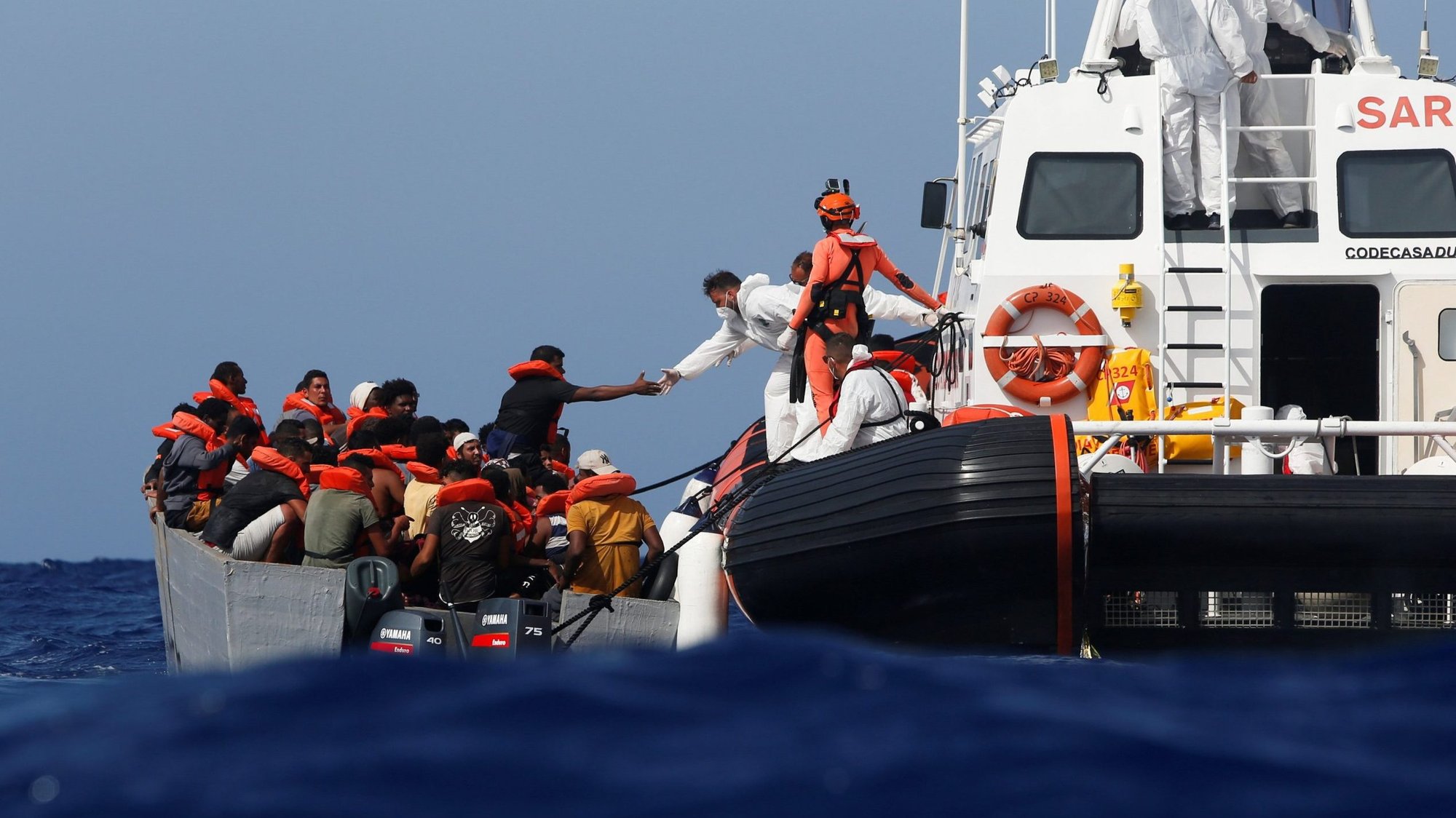 Italian Coast Guard members rescue some migrants on a wooden boat during a joint rescue operation with the German NGO migrant rescue ship Sea-Watch 3 in the western Mediterranean Sea Aug. 2, 2021. (CNS photo/Darrin Zammit Lupi, Reuters)