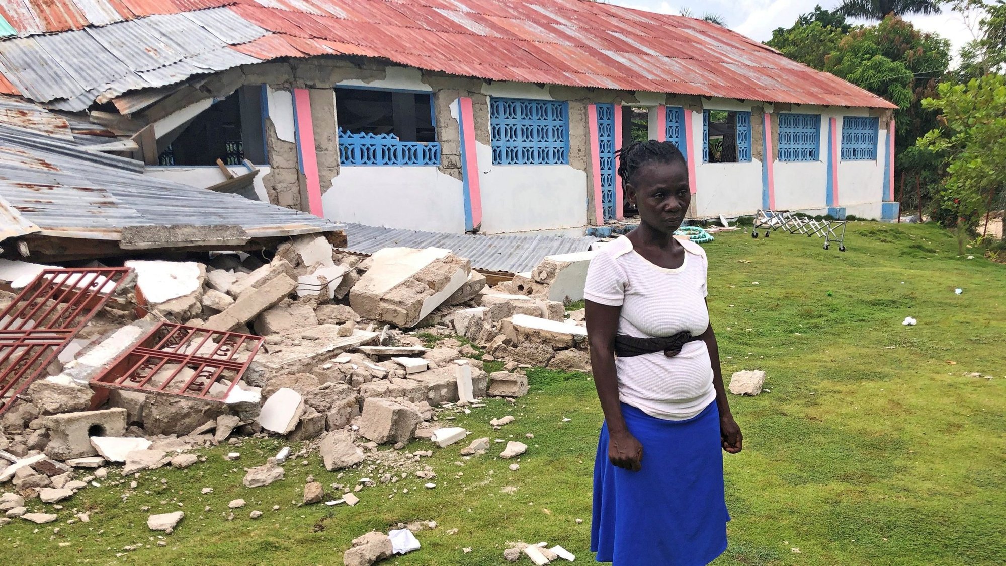 Kettney Francois poses outside the remains of St. Famille du Toirac church in Toirac, Haiti, Aug. 16, 2021. Francois was trampled in a frantic stampede of people trying to escape after a magnitude 7.2 earthquake hit during a funeral Mass at the church. (CNS photo/Laura Gottesdiener, Reuters)