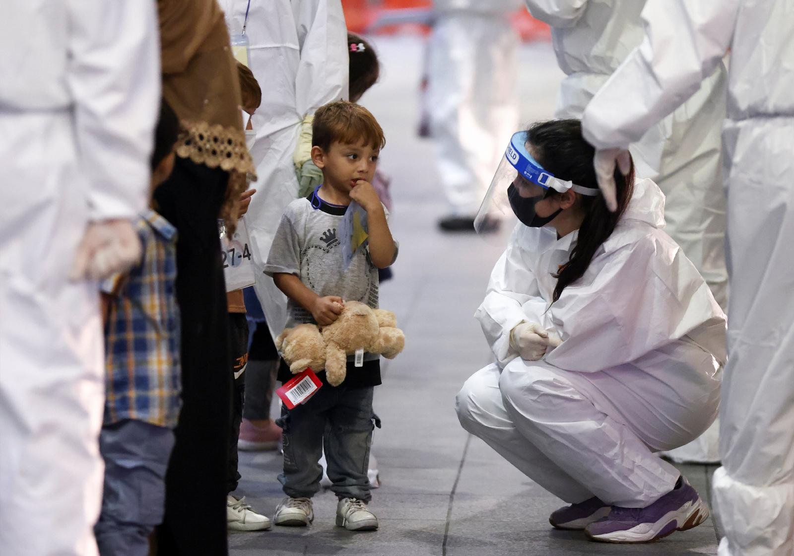 A woman wearing protective gear chats with a child as Afghan evacuees who supported the South Korean government's activities in Afghanistan arrive at Incheon International Airport in South Korea Aug. 26, 2021. (CNS photo/Kim Hong-Ji, Reuters)