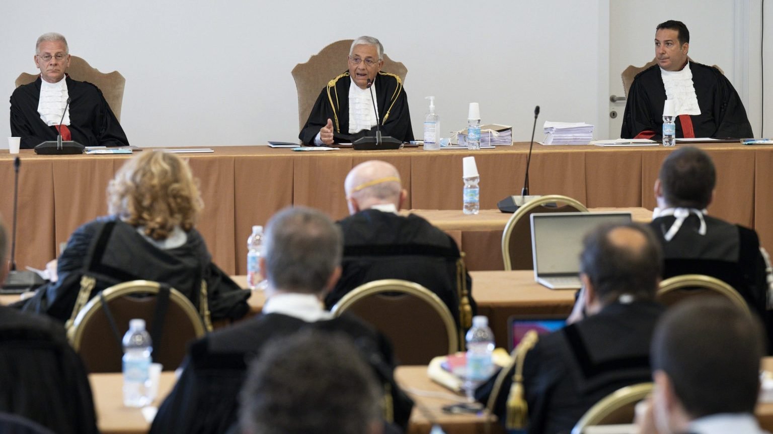 The judges of the Vatican City State criminal court -- Venerando Marano, Giuseppe Pignatone and Carlo Bonzano -- face dozens of lawyers in a makeshift Vatican courtroom July 27, 2021, as the trial of 10 defendants in a financial malfeasance case begins. Cardinal Angelo Becciu is among the defendants. (CNS photo/Vatican Media)