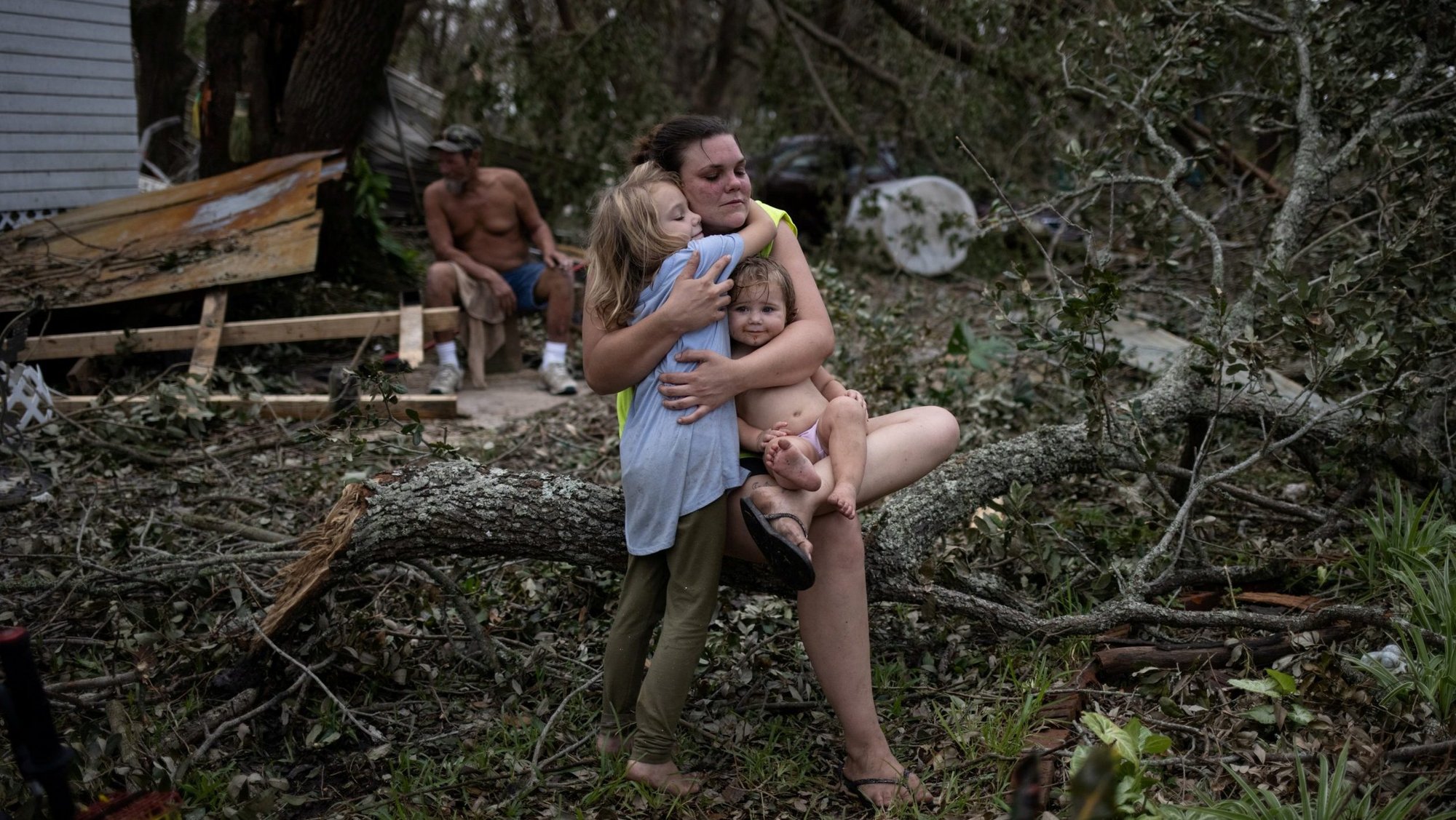 In the aftermath of Hurricane Ida, Tiffany Miller of Golden Meadow, La., embraces her daughter Desilynn, 6, outside their home Sept. 1, 2021, as she holds her 1-year-old godchild, Charleigh. (CNS photo/Adrees Latif, Reuters)