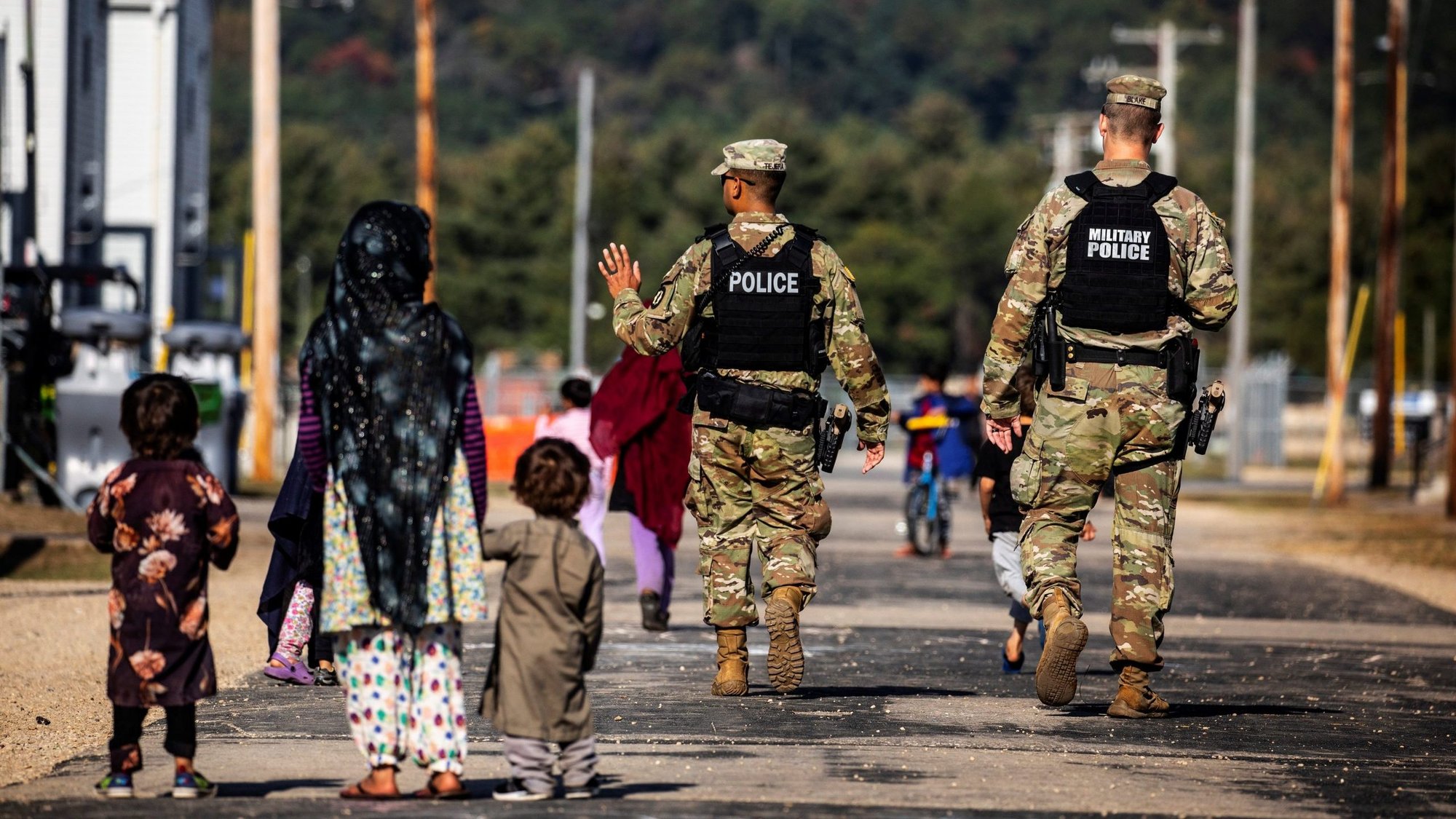 U.S. Military Police walk past Afghan refugees at the Village at Fort McCoy U.S. Army base in Wisconsin Sept. 30, 2021. (CNS photo/Barbara Davidson, pool via Reuters)