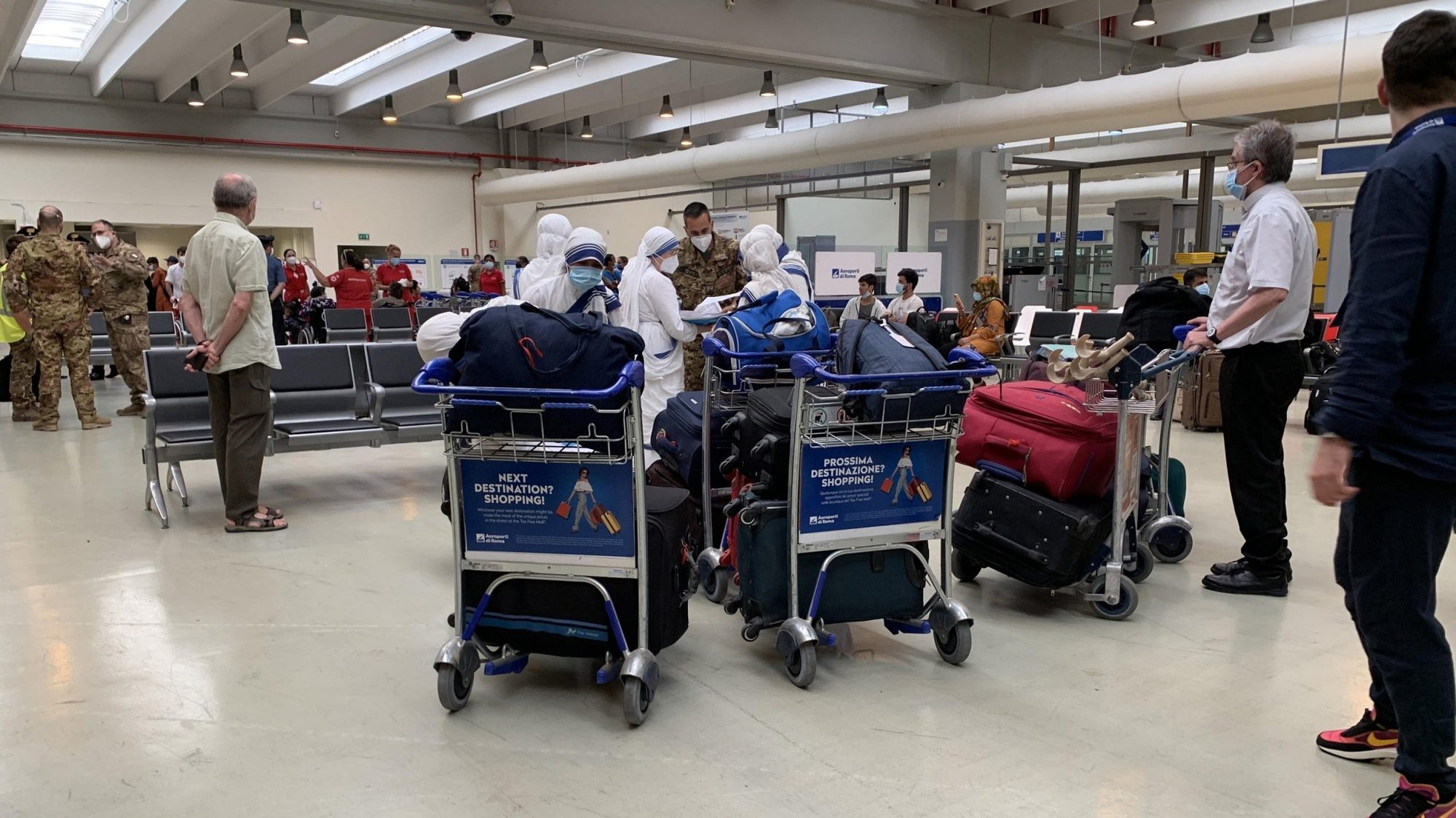 Barnabite Father Giovanni Scalese holds a baggage trolley, right, as he arrives with five Missionaries of Charity nuns at Rome's Fiumicino airport Aug. 25, 2021, after the group was evacuated from Afghanistan. Father Scalese, who was head of the sole Catholic mission in Afghanistan, told the Vatican newspaper that now is a time of waiting for God to indicate a new path for the missionary church in Afghanistan. (CNS photo/ANSA)