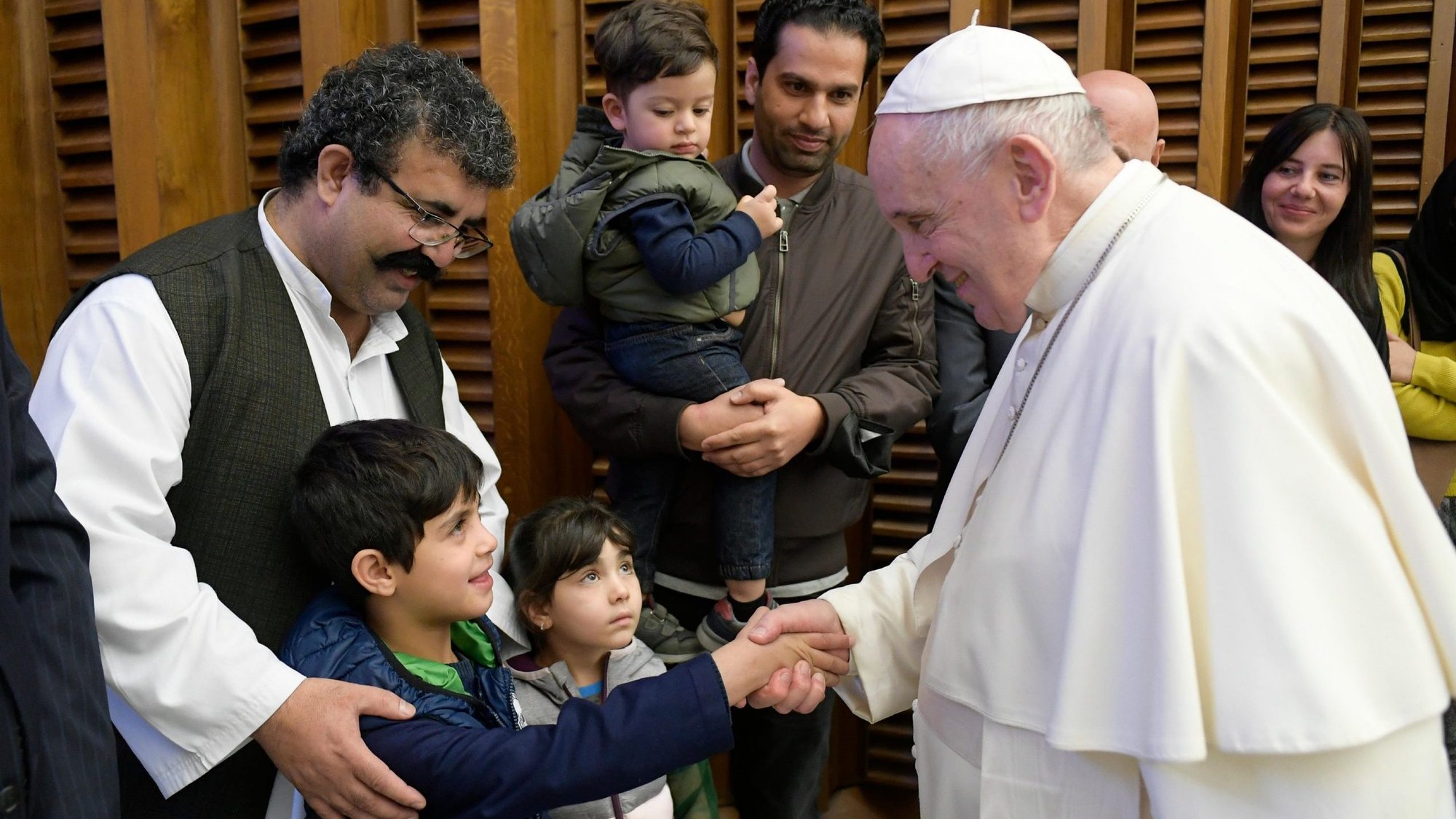 Pope Francis greets a child as he meets families who fled from Afghanistan, during his general audience in the Paul VI hall at the Vatican Oct. 13, 2021. (CNS photo/Vatican Media)