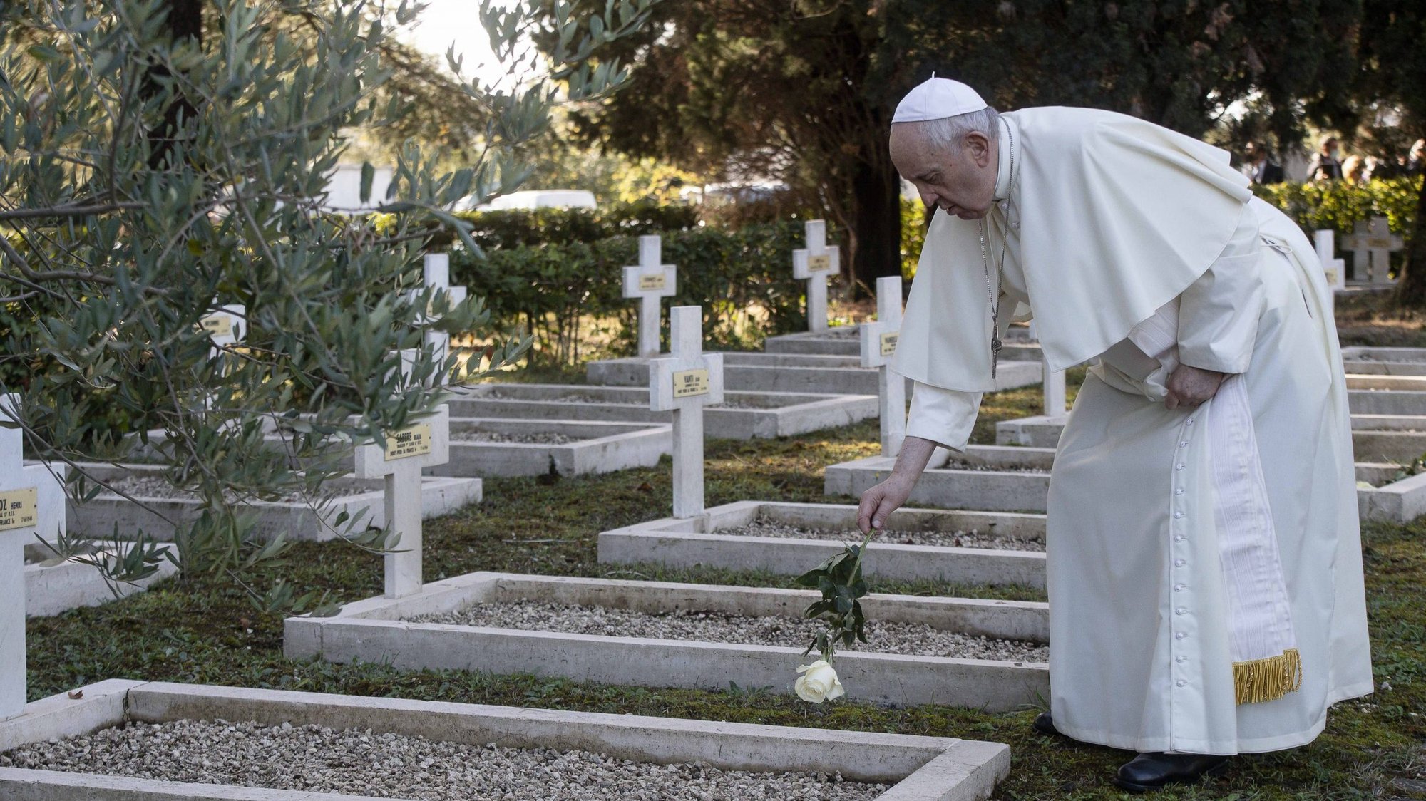 Pope Francis places a white rose on a grave at the French Military Cemetery before celebrating Mass for the feast of All Souls at the cemetery in Rome Nov. 2, 2021. (CNS photo/Vatican Media)
