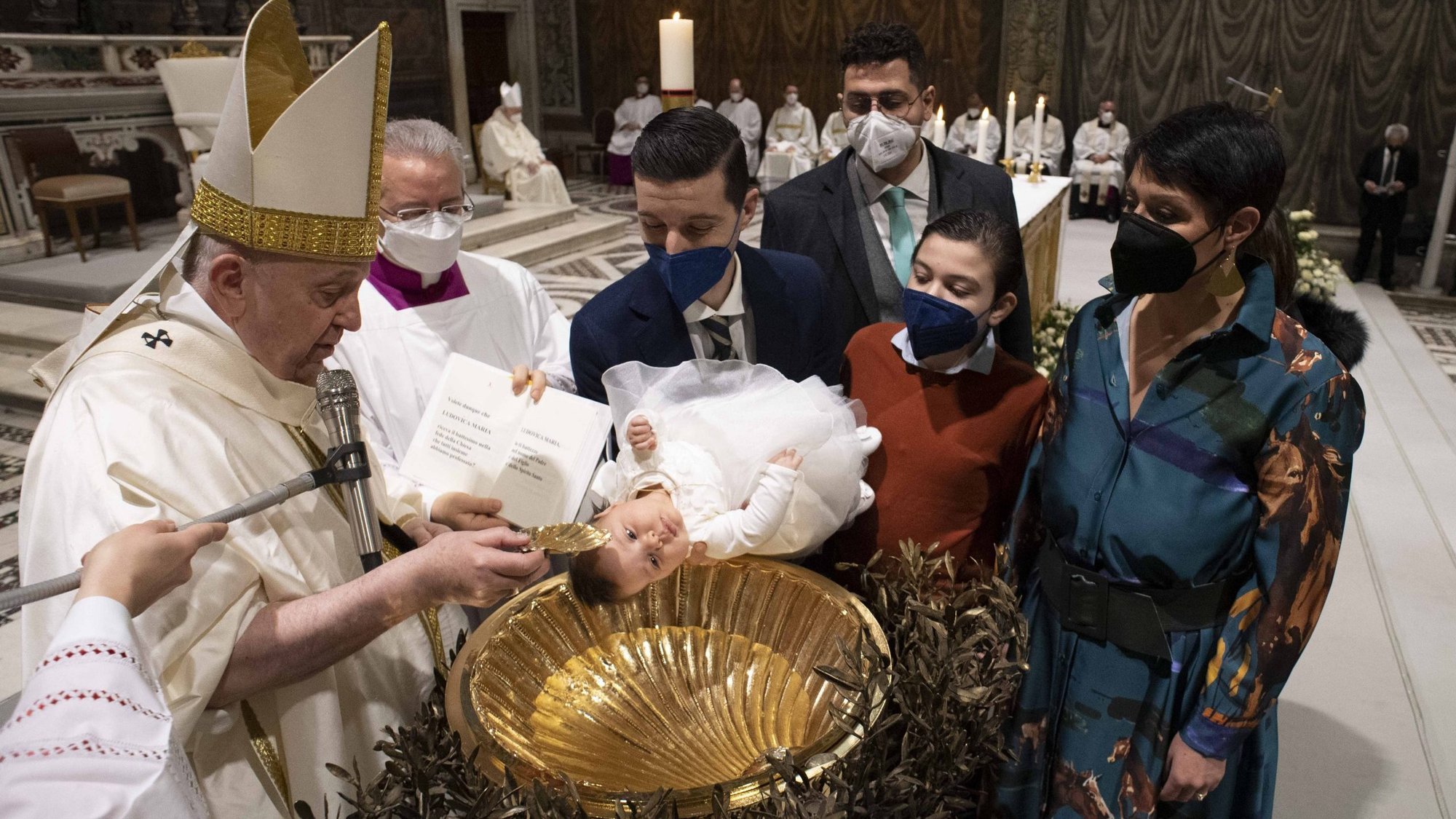 Pope Francis baptizes a baby during Mass marking the feast of the Baptism of the Lord in the Sistine Chapel at the Vatican Jan. 9, 2022. The pope baptized 16 infants. (CNS photo/Vatican Media)