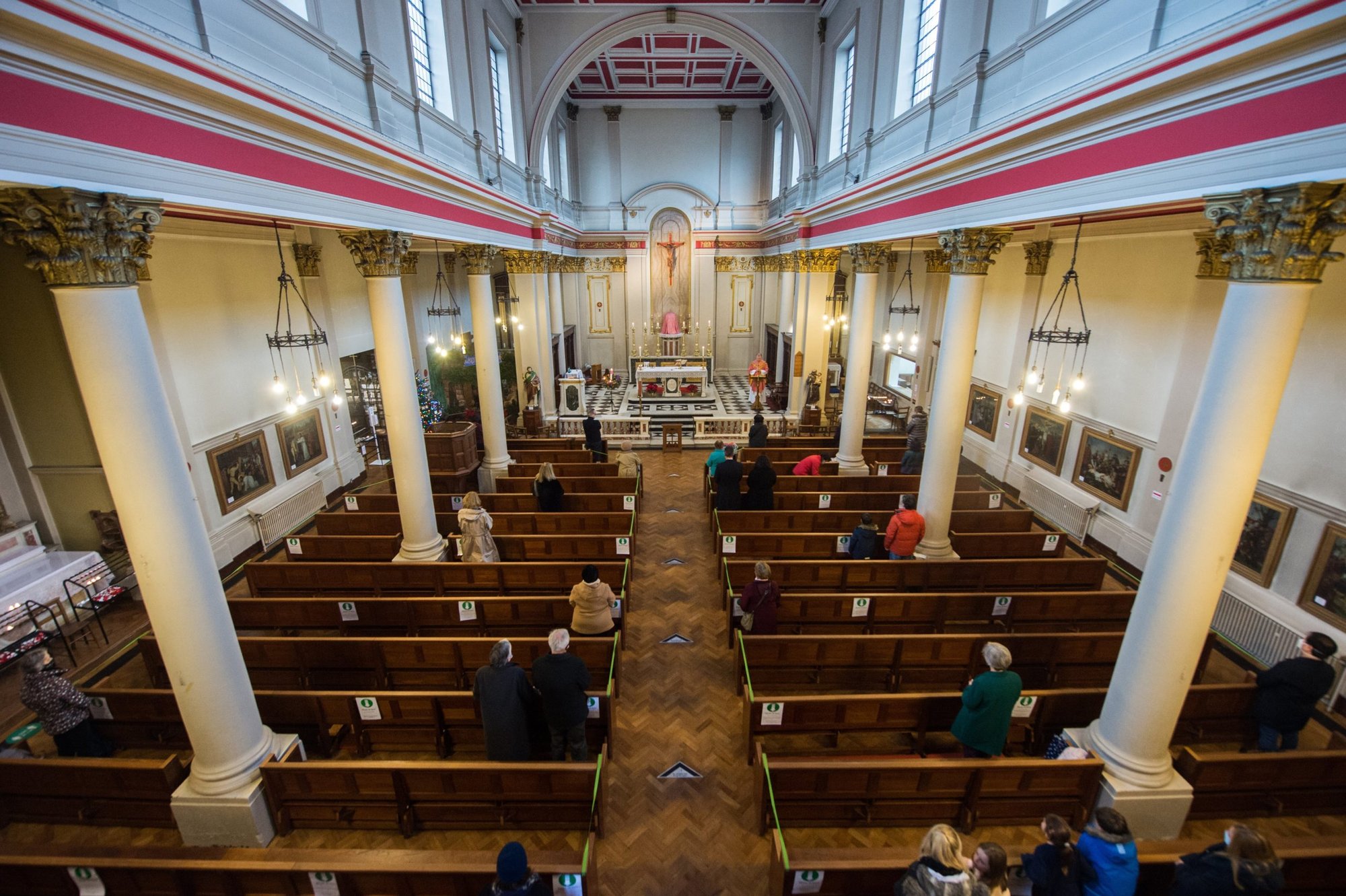 People maintain social distancing while attending Mass in the Church of Our Lady of Grace & St. Edward in London Dec. 13, 2020, during the COVID-19 pandemic. As of Jan. 27, 2022, churches in Britain will not require social distancing, singing will be allowed and holy water fonts can be filled. (CNS photo/Marcin Mazur, courtesy Bishops' Conference of England and Wales)