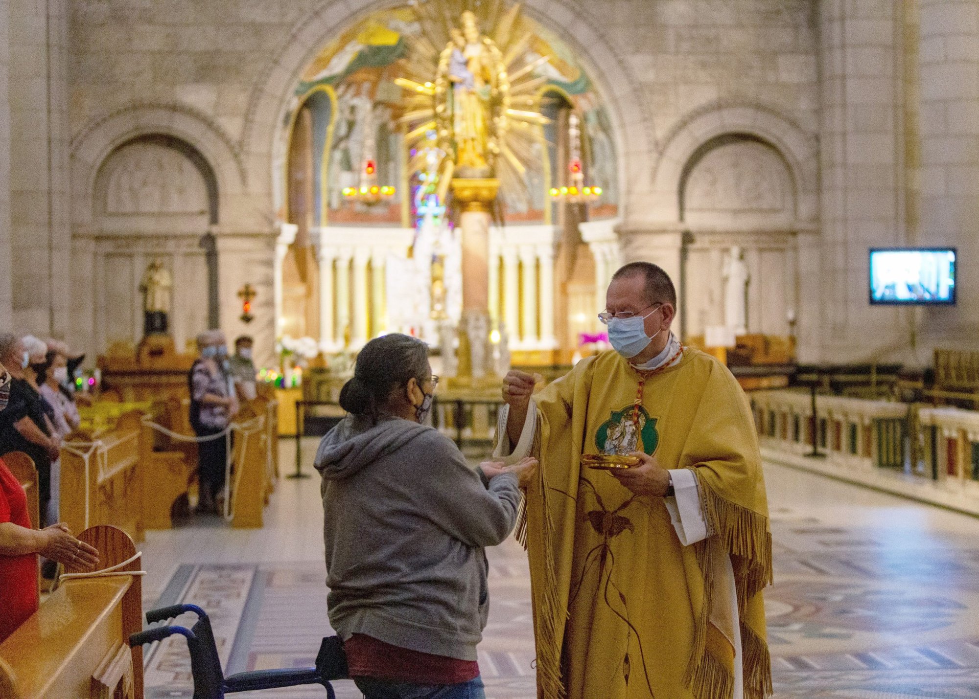 Cardinal Gérald C. Lacroix of Quebec distributes Communion to an Innu woman during Mass on First Nations Sunday at the Shrine of Ste. Anne de Beaupré June 27, 2021. More than two dozen Indigenous delegates, accompanied by a handful of Canadian bishops, plan to meet with Pope Francis at the Vatican March 28-April 1. (CNS photo/Philippe Vaillancourt, Presence)