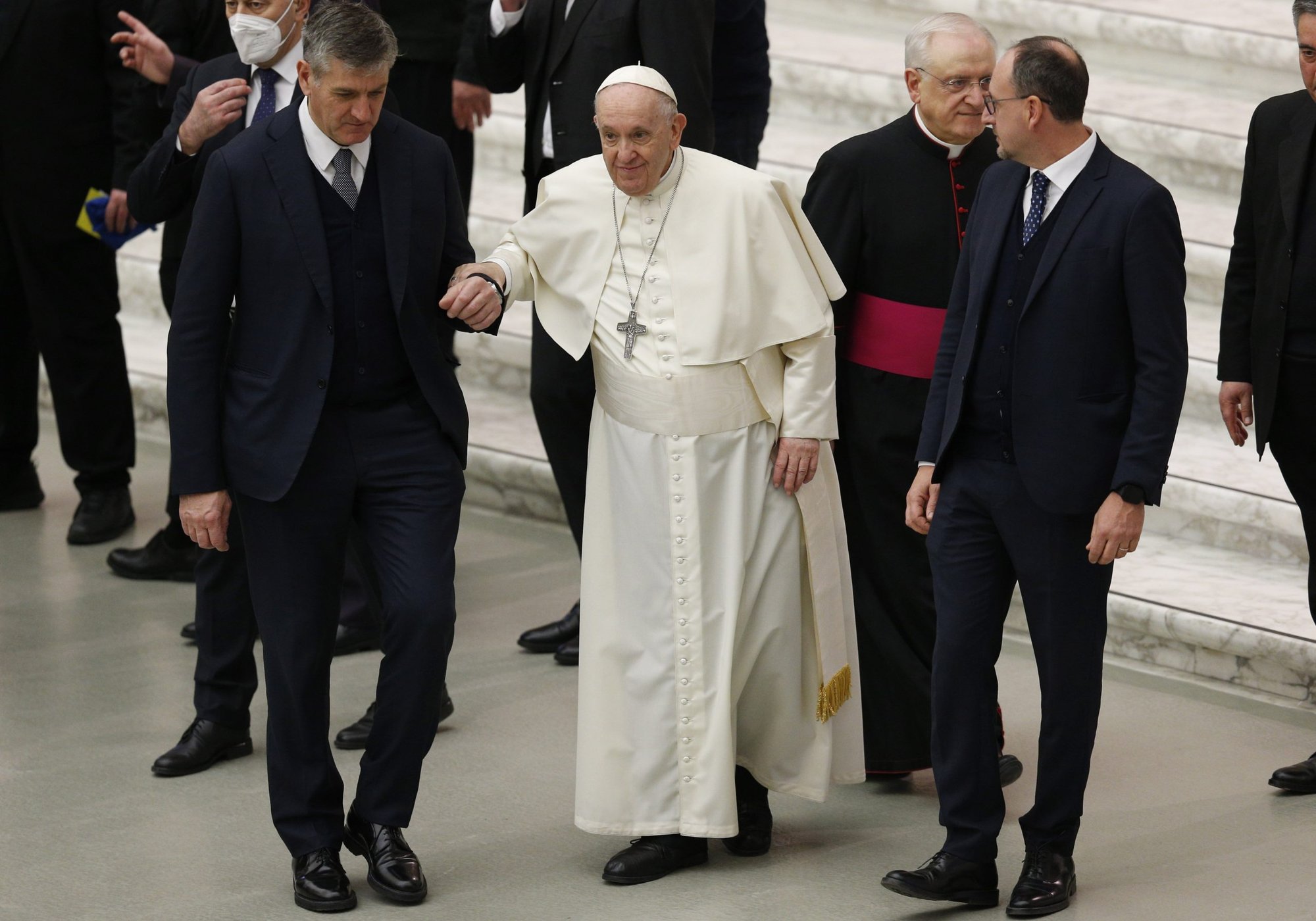 Pope Francis holds the arm of his aide, Sandro Mariotti, was he walks during his general audience in the Paul VI hall at the Vatican in this Jan. 26, 2022, file photo. The Vatican announced that the pope will not travel to Florence Feb. 27 because of severe knee pain. (CNS photo/Paul Haring)