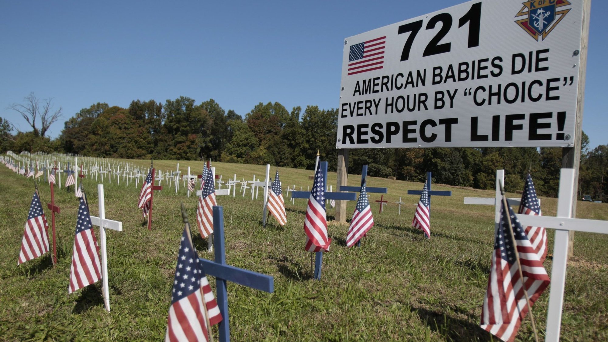 A sign and small wooden crosses with U.S. flags are seen in a field near Jesus the Divine Word Church in Huntington, Md., Oct. 9, 2011. (CNS photo/Bob Roller)