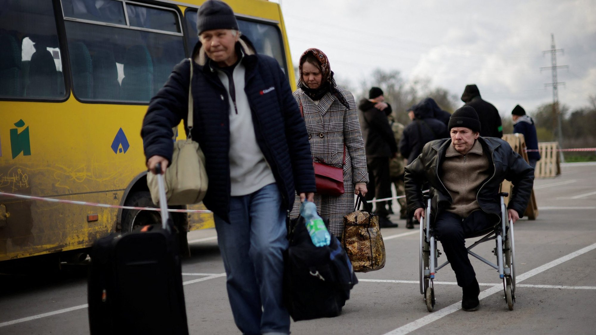 Ukrainian refugees in Zaporizhzhia, Ukraine, walk towards a registration center for internally displaced people April 21, 2022, after arriving in a small convoy that crossed through a territory held by Russian forces. (CNS photo/Ueslei Marcelino, Reuters)