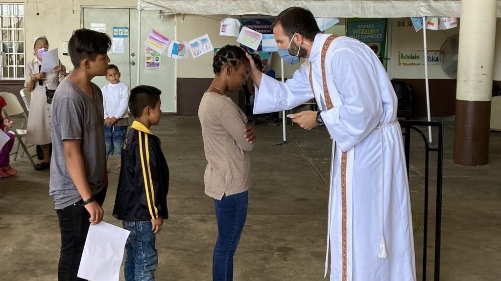 Jesuit Father Brian Strassburger blesses a migrant at Mass in Reynosa, Mexico, May 24, 2022. The migrants attending the Mass were waiting at the U.S.-Mexico border for the United States to lift a health provision known as Title 42 and allow them to make asylum claims. (CNS photo/David Agren)