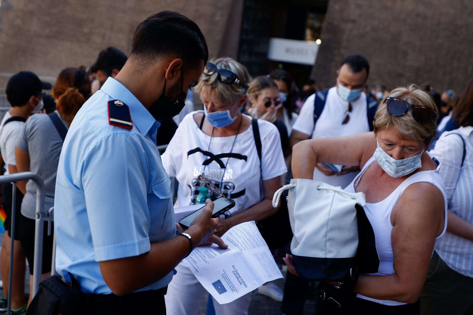 People have their "green pass," signifying vaccination against COVID-19 or a negative test taken within 48 hours, checked before entering the Vatican Museums at the Vatican in this Aug. 6, 2021, file photo. The Vatican has updated its COVID-19 protocols, allowing most employees and visitors to enter Vatican City State without a vaccination certificate or proof of recovery. (CNS photo/Guglielmo Mangiapane, Reuters)