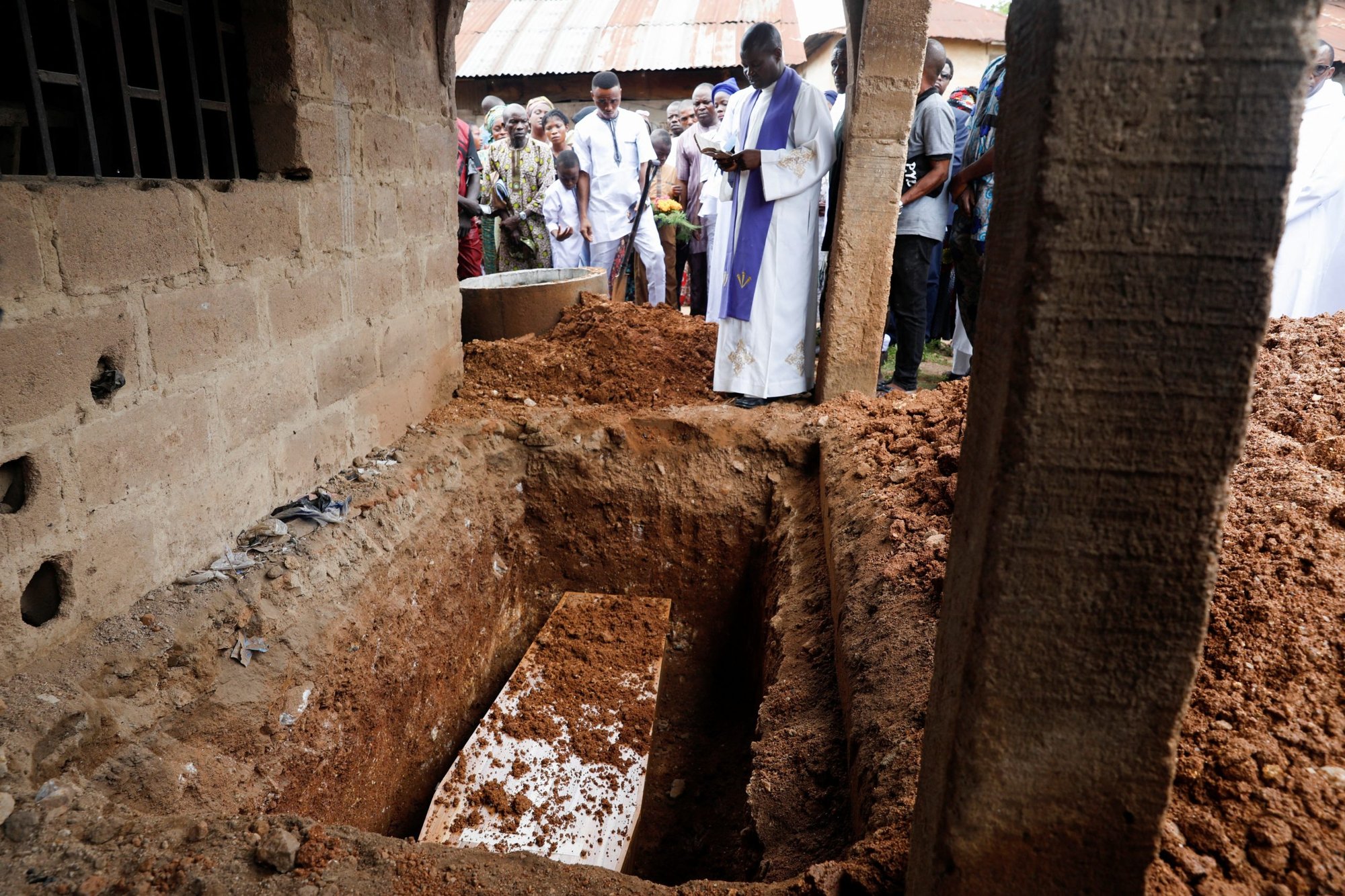 A priest prays over a casket during a during a burial outside St. Francis Xavier Church in Owo, Nigeria, June 17, 2022. The Mass was for at least 50 victims killed in a June 5 attack by gunmen during Mass at the church. (CNS photo/Temilade Adelaja, Reuters)