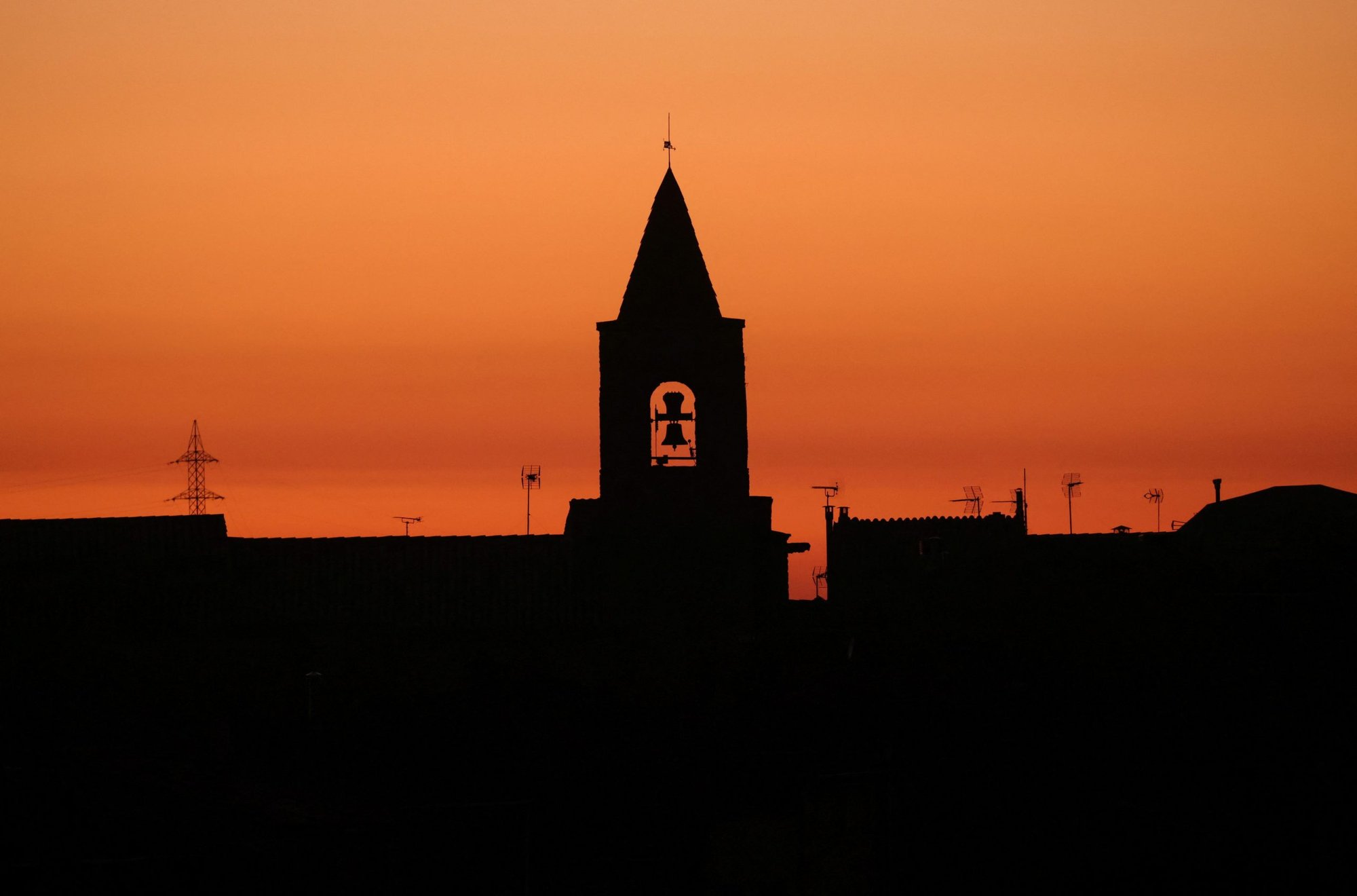 The bell tower of a church is seen during sunset in the village of Montmaneu, Spain, Jan. 28, 2022. (CNS photo/Nacho Doce, Reuters)