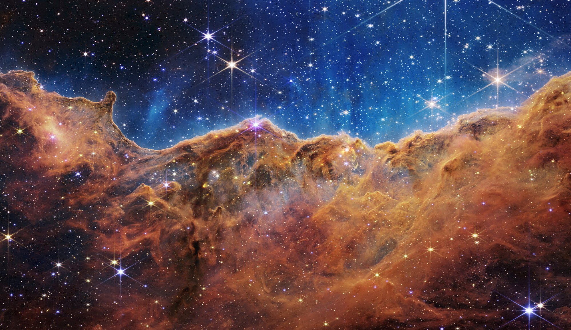 The "Cosmic Cliffs" of the Carina Nebula are seen in an image released by NASA released July 12, 2022. The "cliffs" are divided horizontally by an undulating line between a cloudscape forming a nebula along the bottom portion and a comparatively clear upper portion. The image is from data provided by NASA's James Webb Space Telescope, a revolutionary apparatus designed to peer through the cosmos to the dawn of the universe. Speckled across both portions is a starfield, showing innumerable stars of many sizes. (CNS photo/NASA, ESA, CSA, STScI, Webb ERO Production Team, Handout via Reuters)