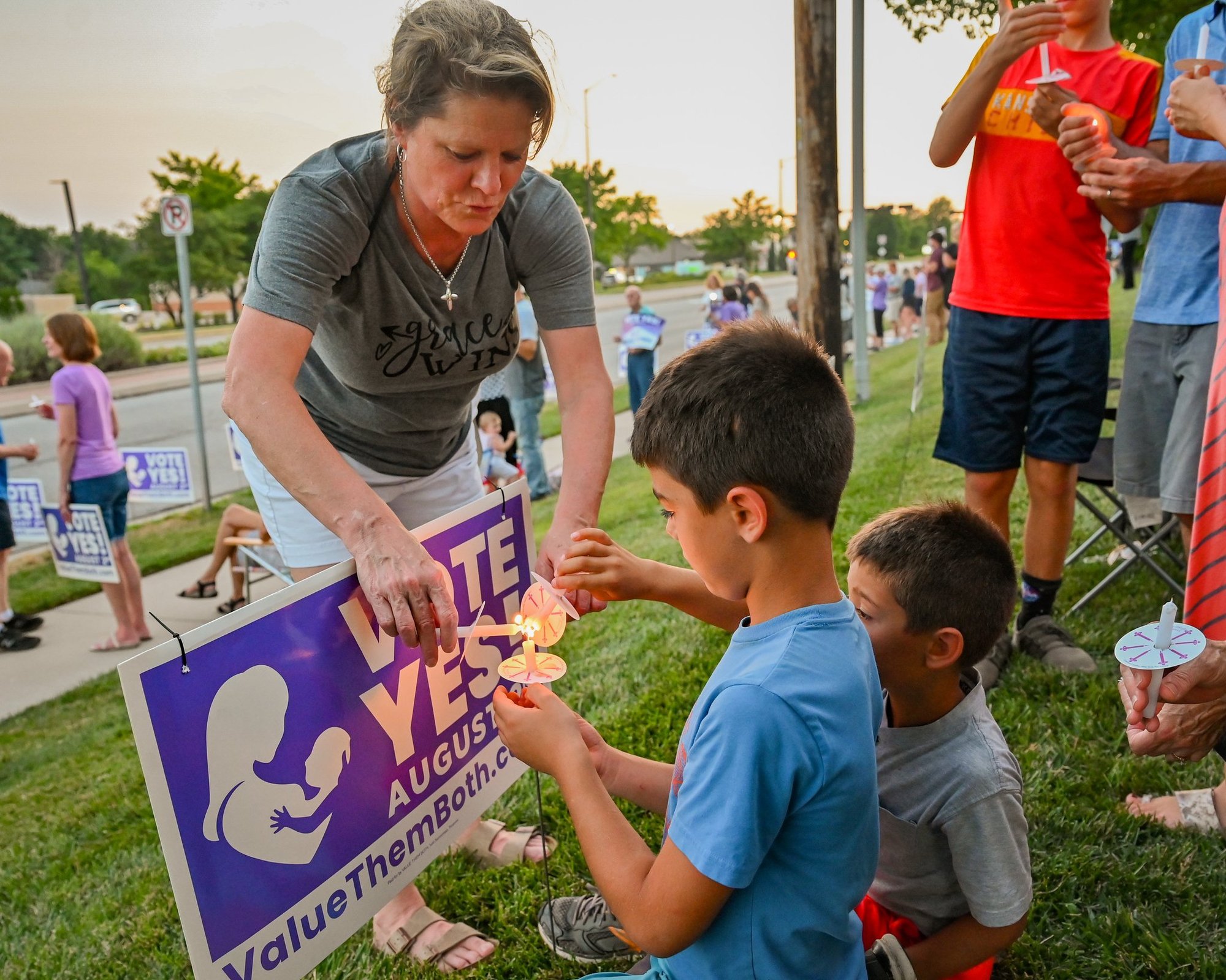 A woman helps two young boys light candles during a "Value Them Both" sidewalk vigil in Olathe, Kan., Aug. 1, 2022. Voters rejected a ballot referendum that would have amended the state constitution to say there is no constitutional right to abortion in Kansas. (CNS photo/Kathryn White, The Leaven)