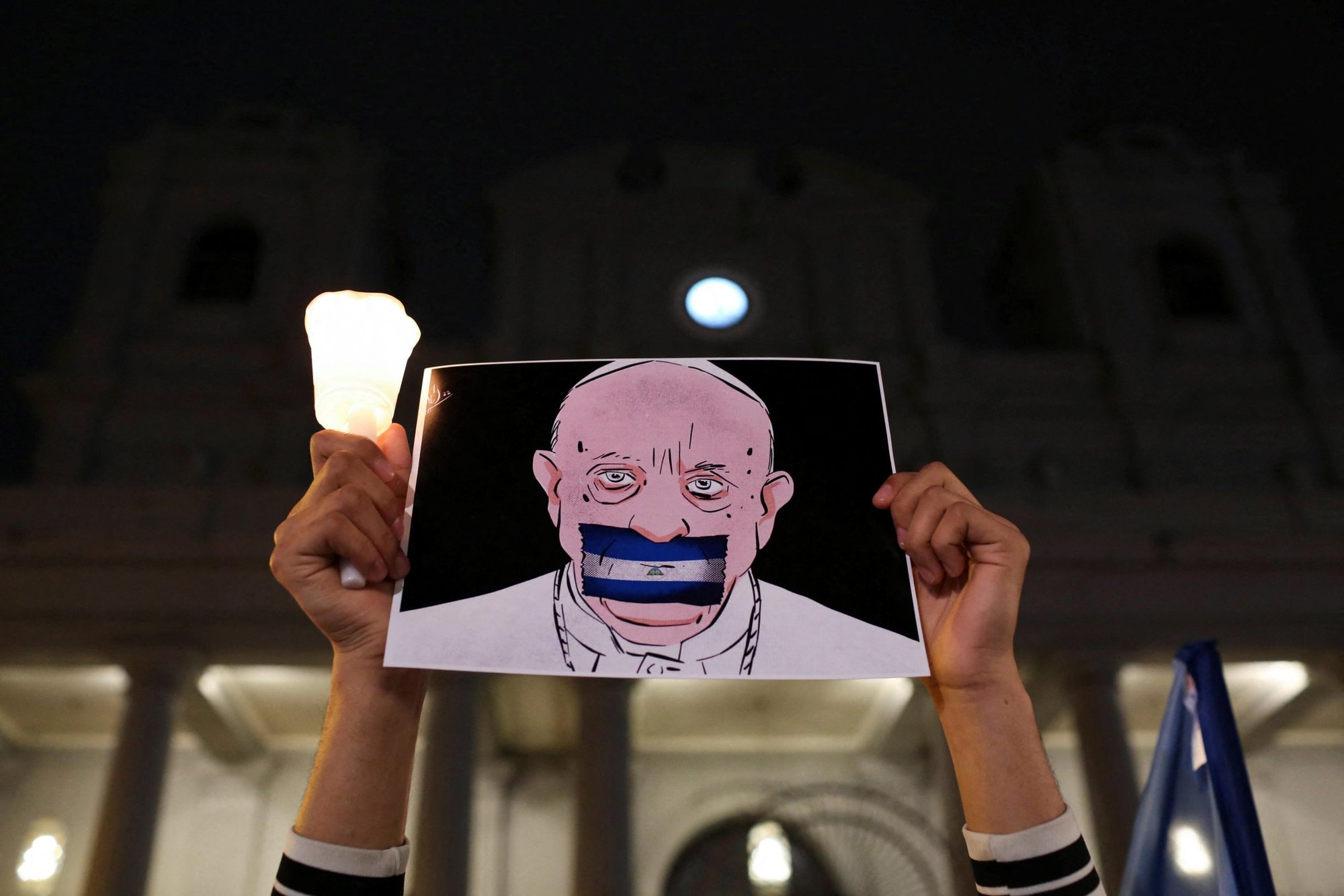 A Nicaraguan exiled in Costa Rica holds up a drawing of Pope Francis with a Nicaraguan flag covering his mouth during the "Vigil of Faith and Freedom" outside the Metropolitan Cathedral in San Jose, Costa Rica, Aug. 19, 2022. (CNS photo/Mayela Lopez, Reuters)