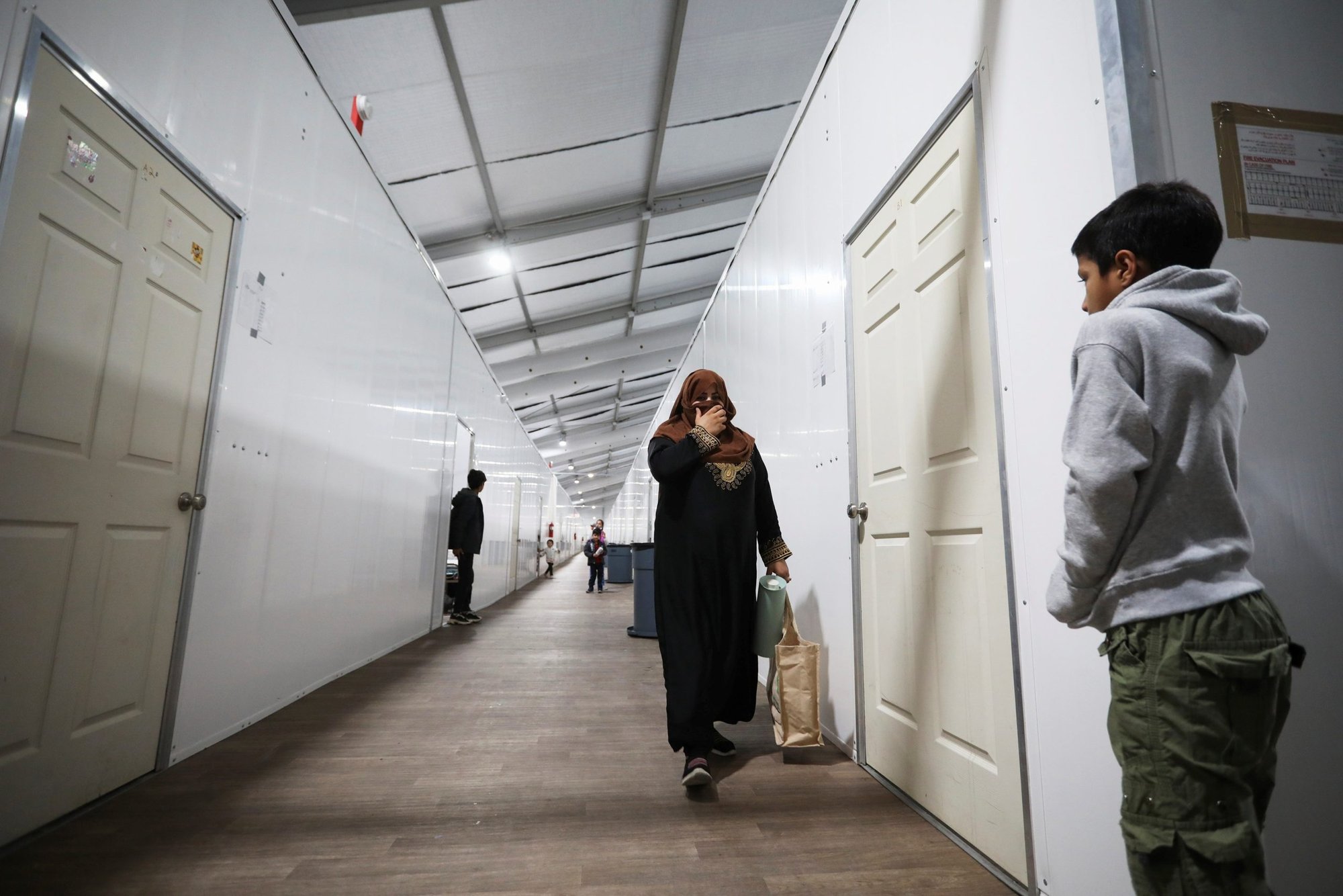 Afghan refugees at Joint Base McGuire-Dix- Lakehurst in New Jersey walk inside a housing facility where they are temporarily living Dec. 2, 2021. (CNS photo/Barbara Davidson, Reuters)