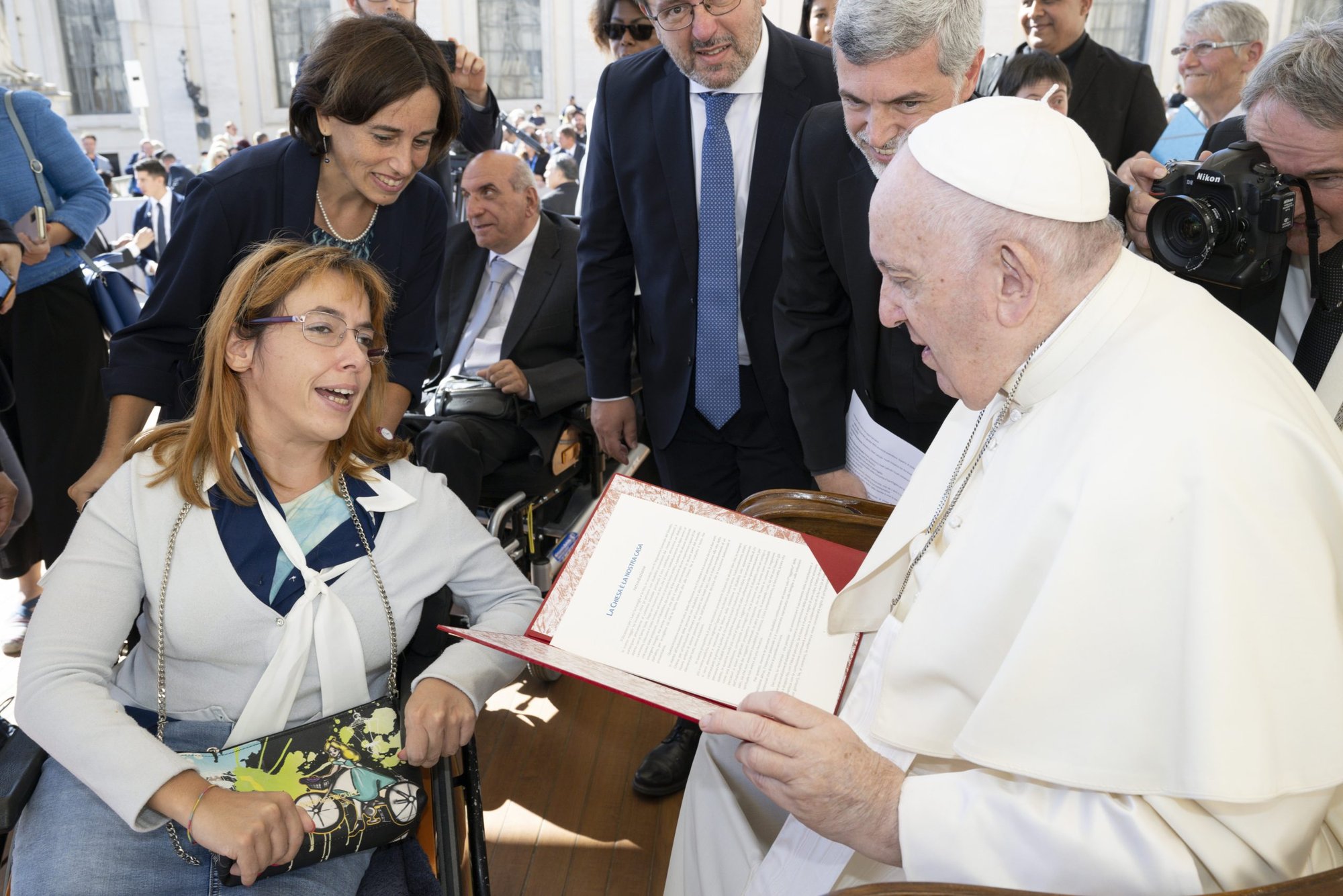 Pope Francis accepts a document on people with disabilities from Giulia Cirillo, a member of the Sant'Egidio community, at the end of the general audience in St. Peter's Square at the Vatican Sept. 21, 2022. People with disabilities submitted a draft document to the Synod of Bishops on the needs of people with disabilities and their contributions to the life of the church. (CNS photo/Vatican Media)