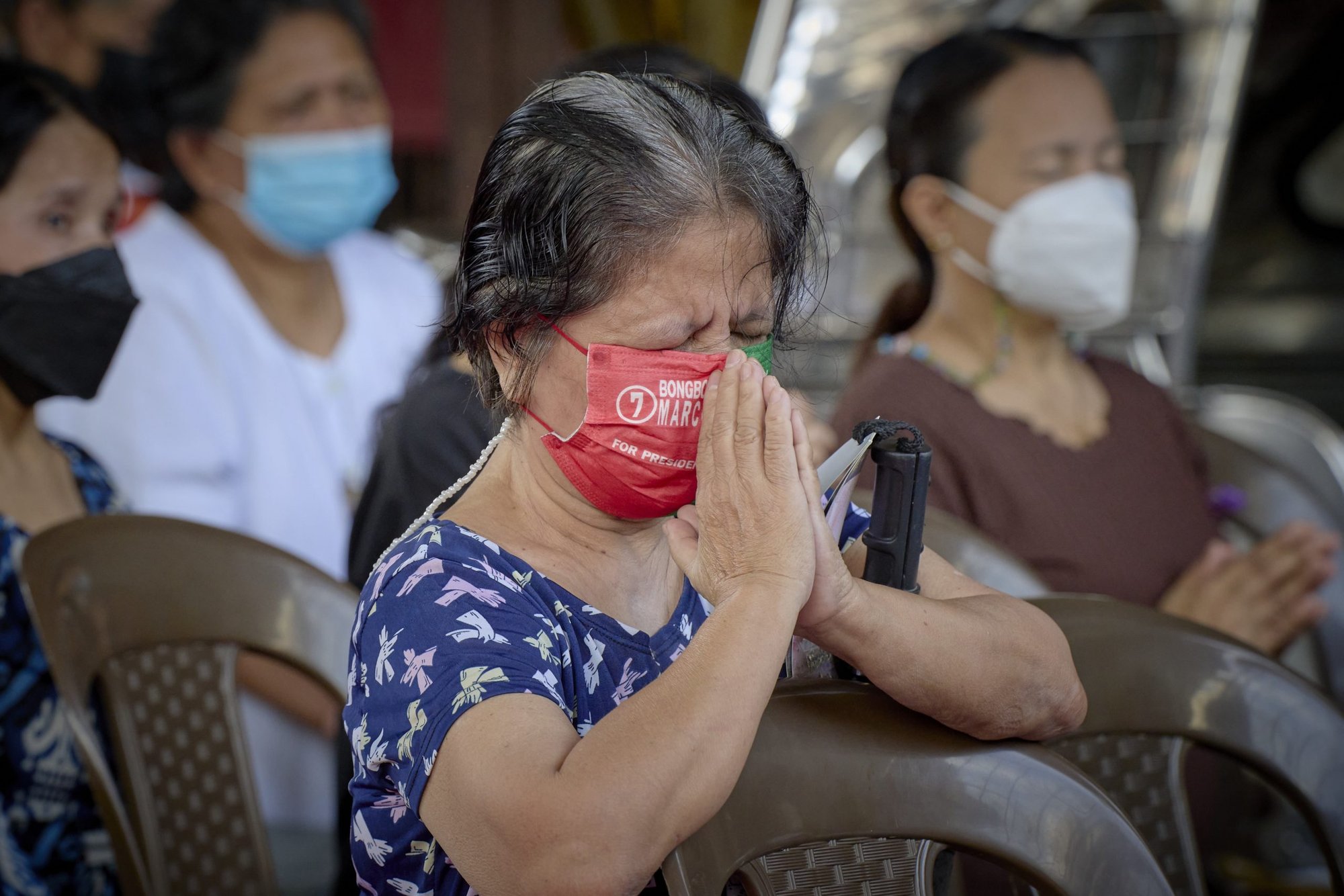 A woman wearing a mask supporting Philippine President Ferdinand "Bongbong" Marcos Jr., prays during Mass in in Manila Sept. 18, 2022. Marcos was elected president of the Philippines in a May 2022 election despite opposition from many church leaders. Marcos' father ruled the Philippines under martial law until his ouster by pro-democracy activists in 1986. (CNS photo/Paul Jeffrey)
