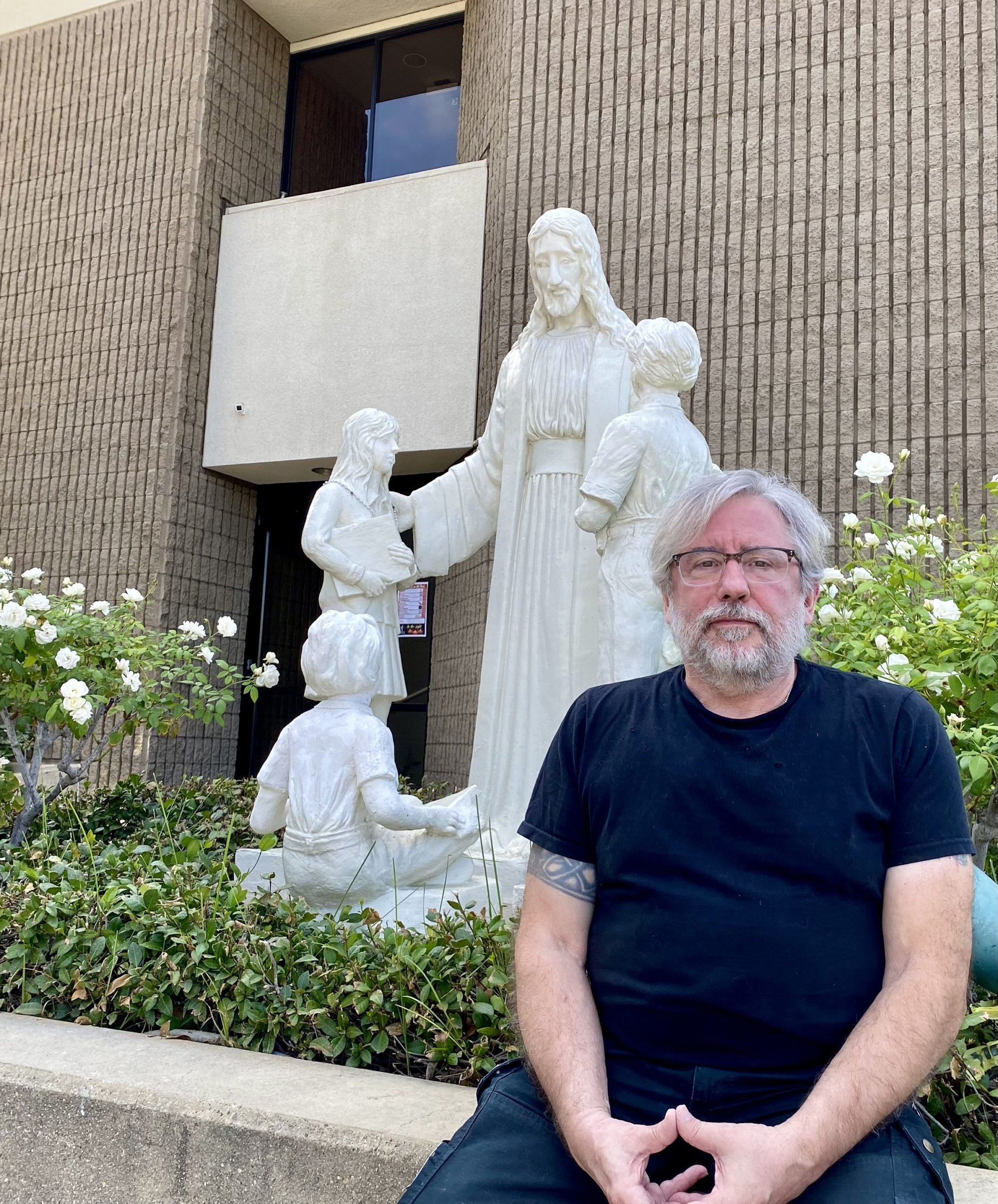 Michael Stucchi poses in front of the restored statue of Jesus with children at St. Mel's Church in Woodland Hills. (Tom Hoffarth)