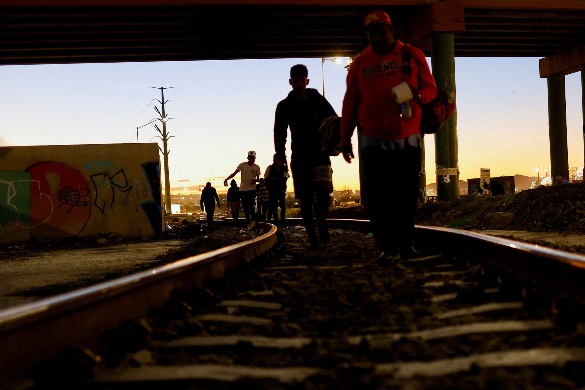 Venezuelan migrants in Ciudad Juarez, Mexico, walk on the train tracks near the Paso del Norte International border bridge Oct. 21, 2022. (CNS photo/Jose Luis Gonzalez, Reuters)