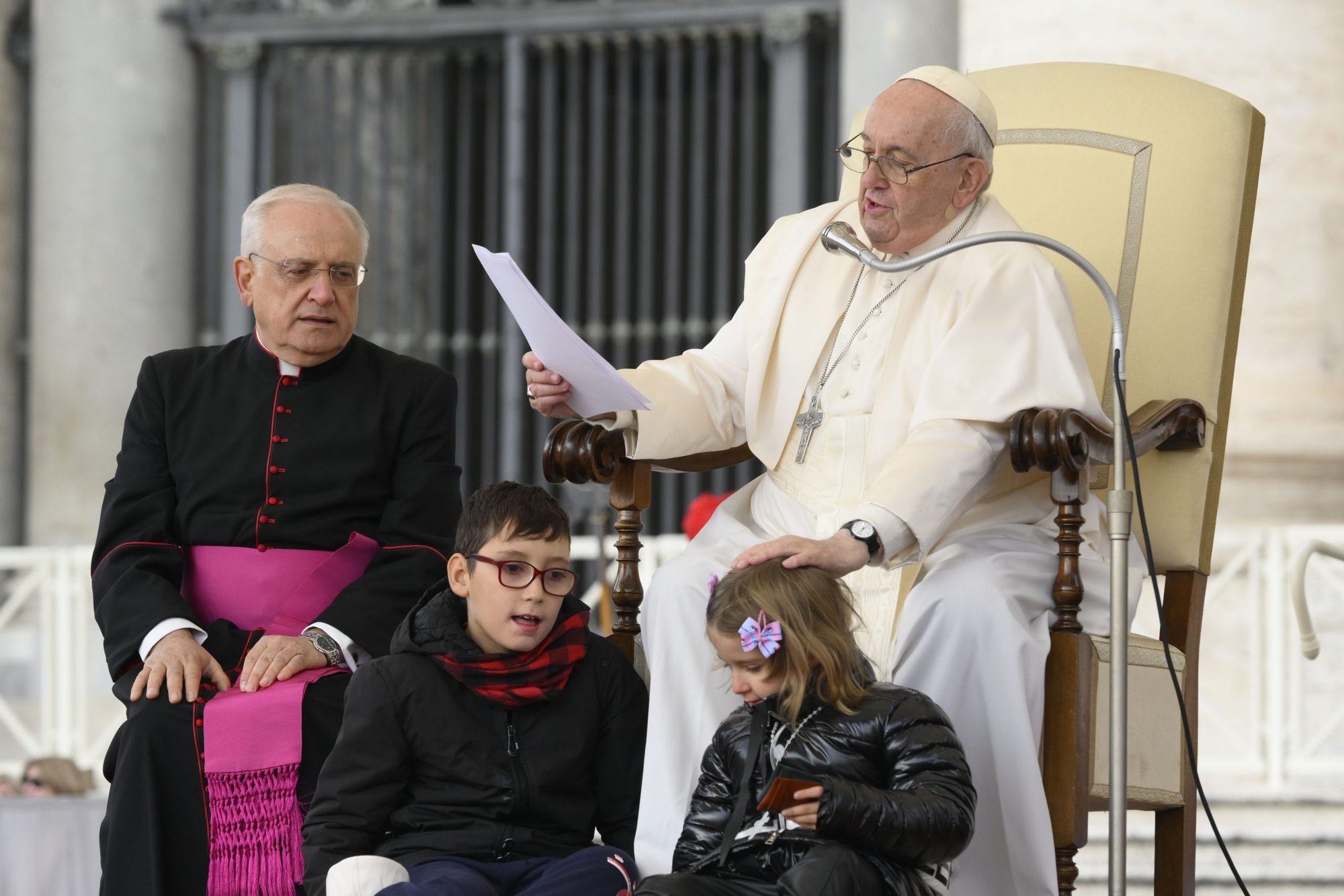 Pope Francis pats the head of a girl after she and another child ran up on to the stage during his weekly general audience in St. Peter's Square Nov. 9, 2022. (CNS photo/Vatican Media)