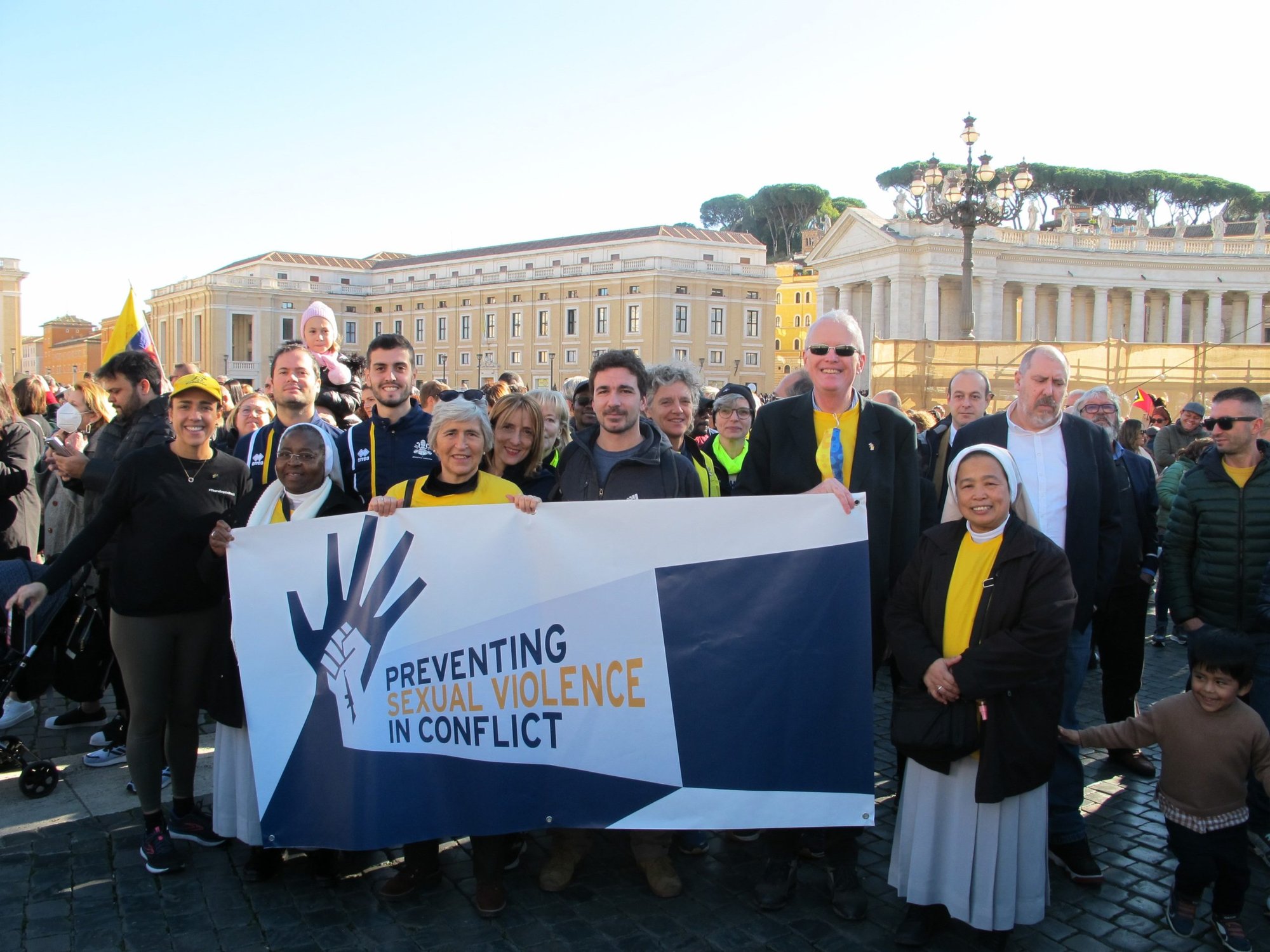 Christopher Trott, the British ambassador to the Holy See, right, and Chiara Porro, Australian ambassador to the Holy See, and others hold a banner calling for the prevention of sexual violence as a weapon of war as they pose for a photo in St. Peter's Square at the Vatican Nov. 27, 2022. (CNS photo courtesy of the British Embassy to the Holy See)