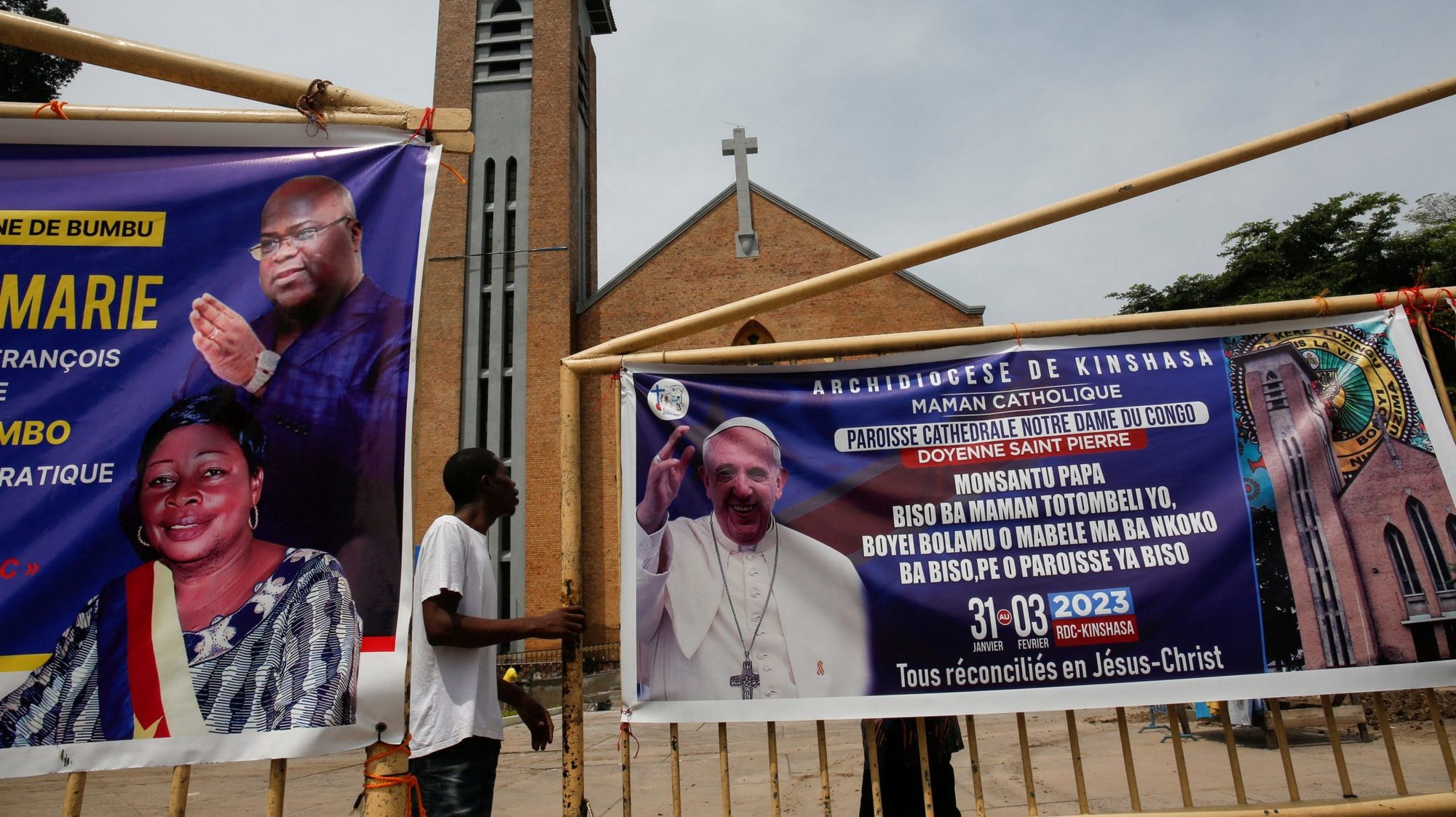 A man stands next to banners of Pope Francis and Congolese President Felix Tshisekedi at the entrance to Our Lady of the Congo Cathedral in Kinshasa Jan. 30, 2023. The pope will attend a meeting and prayer service with priests, religious and seminarians at the cathedral Feb. 2. (OSV News photo/Luc Gnago, Reuters)
