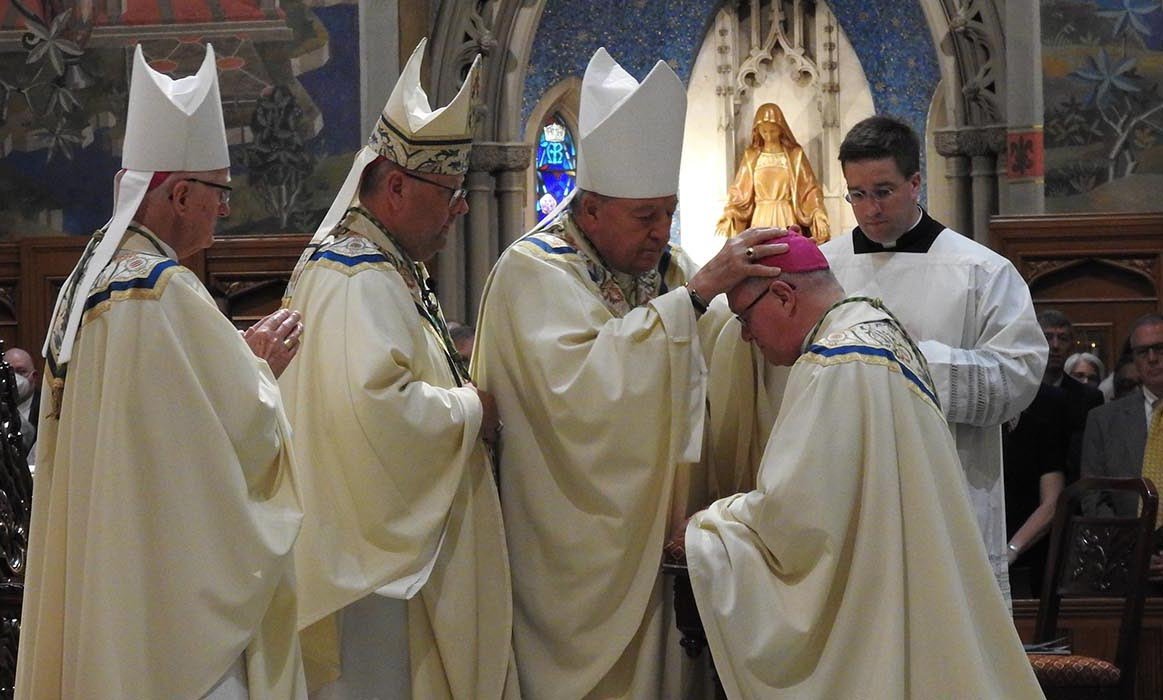 Retired Auxiliary Bishop Roger W. Gries of Cleveland lays hands on Bishop Michael G. Woost during his episcopal ordination as an auxiliary for Cleveland at the Cathedral of St. John the Evangelist Aug. 4, 2022. Gries served as a co-consecrator at Woost’s episcopal ordination. (CNS/Carol Kovach, Northeast Ohio Catholic)