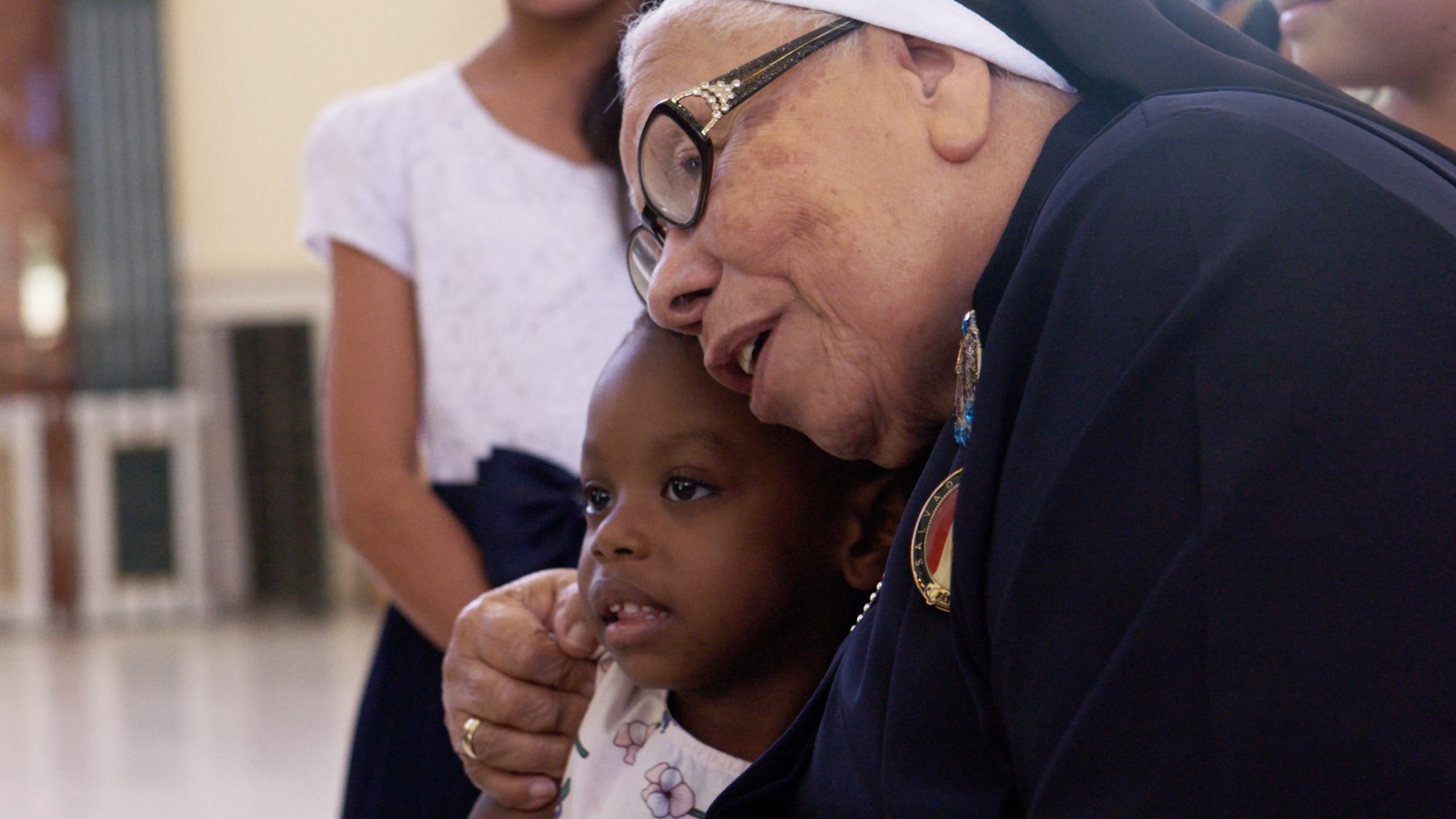 The late Sister Maria Rosa Leggol hugs a child in a scene from “With this Light.” (Miraflores Films)