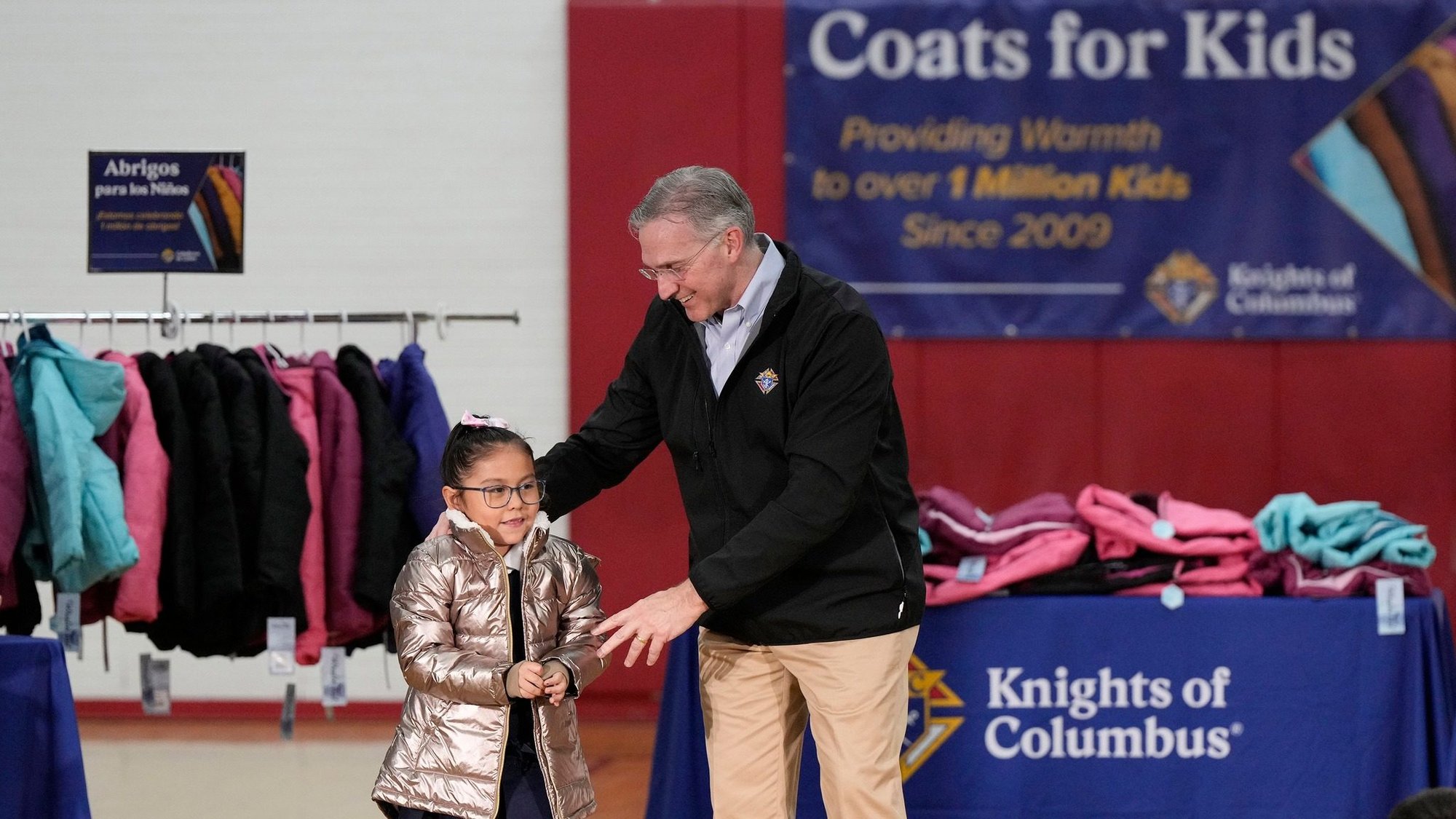 During a celebration of the Coats for Kids program, Supreme Knight Patrick E. Kelly presents the 1 millionth coat to 1st grader Lexi Cordova at Annunciation Catholic School in Denver, Colorado, Nov. 6, 2023. The Knights began the program in 2009 and were marking giving away 1 million coats. (Photo by Knights of Columbus/Paul Haring)