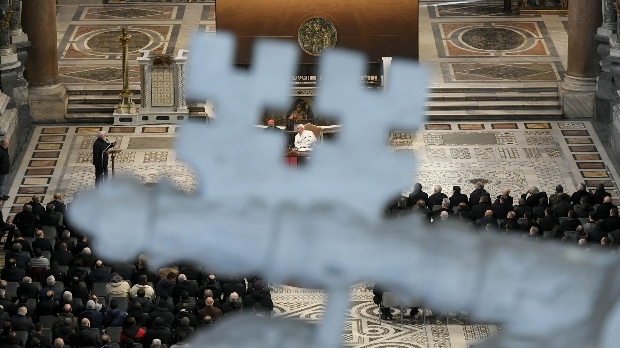 Pope Francis is seen through a detail of a sculpture as he meets with priests and deacons working in the Diocese of Rome Jan. 13, 2024, in Rome's Basilica of St. John Lateran. (CNS photo/Vatican Media)
