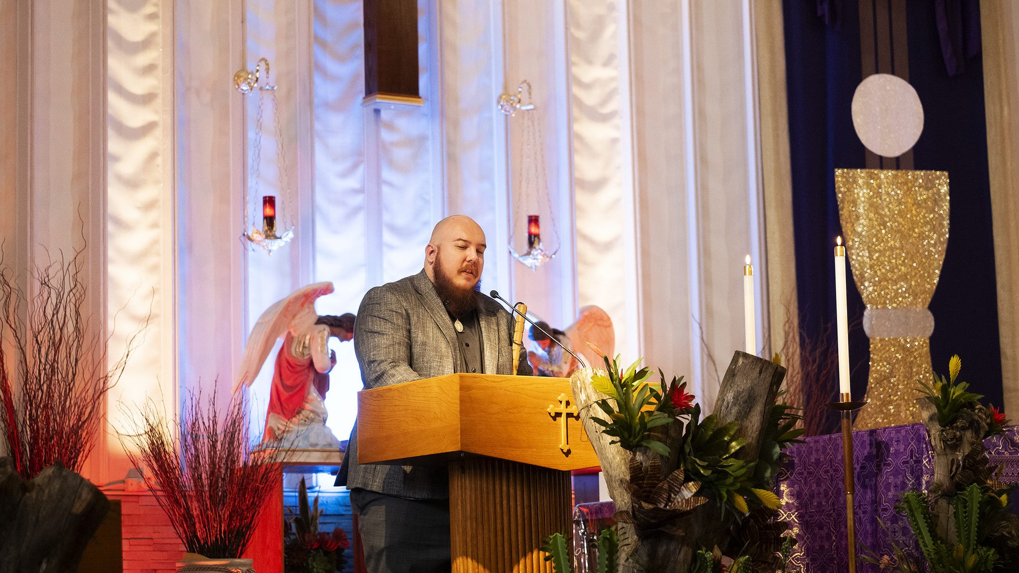 Ryan Rohrich, who lost his sight after being diagnosed with a rare cancerous tumor, recites a reading using braille during a recent Mass at St. John of God Church in Norwalk. (Victor Alemán)