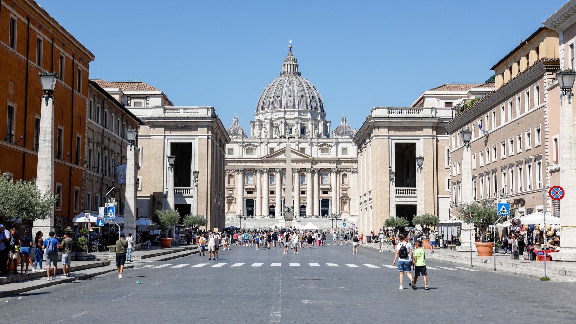 Pilgrims and tourists walk along the Via della Conciliazione toward St. Peter's Square and St. Peter's Basilica Aug. 15, 2023. The broad avenue is lined with many Vatican-owned buildings either used for Vatican offices and residences or rented out to earn money. (CNS photo/Lola Gomez)