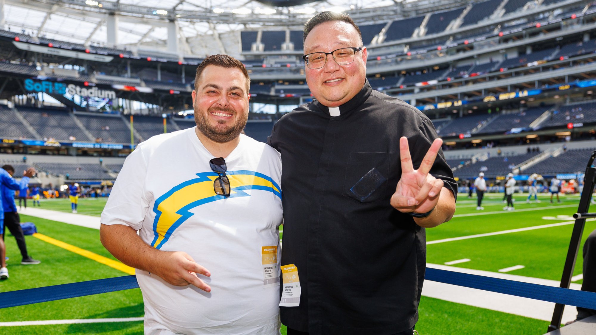 Father Richard Sunwoo, right, poses with Niko Rudela, the brother of Father Marko Rudela, during a preseason Chargers game on Aug. 17. (Los Angeles Chargers)