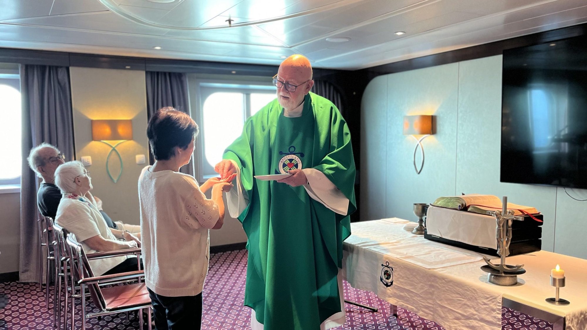 Father Bill Reynolds, a retired priest of the Diocese of Davenport, Iowa, and a longtime maritime minister, is pictured in an undated photo distributing Communion during a Mass he celebrated aboard a cruise ship. (OSV News/courtesy Father Reynolds)