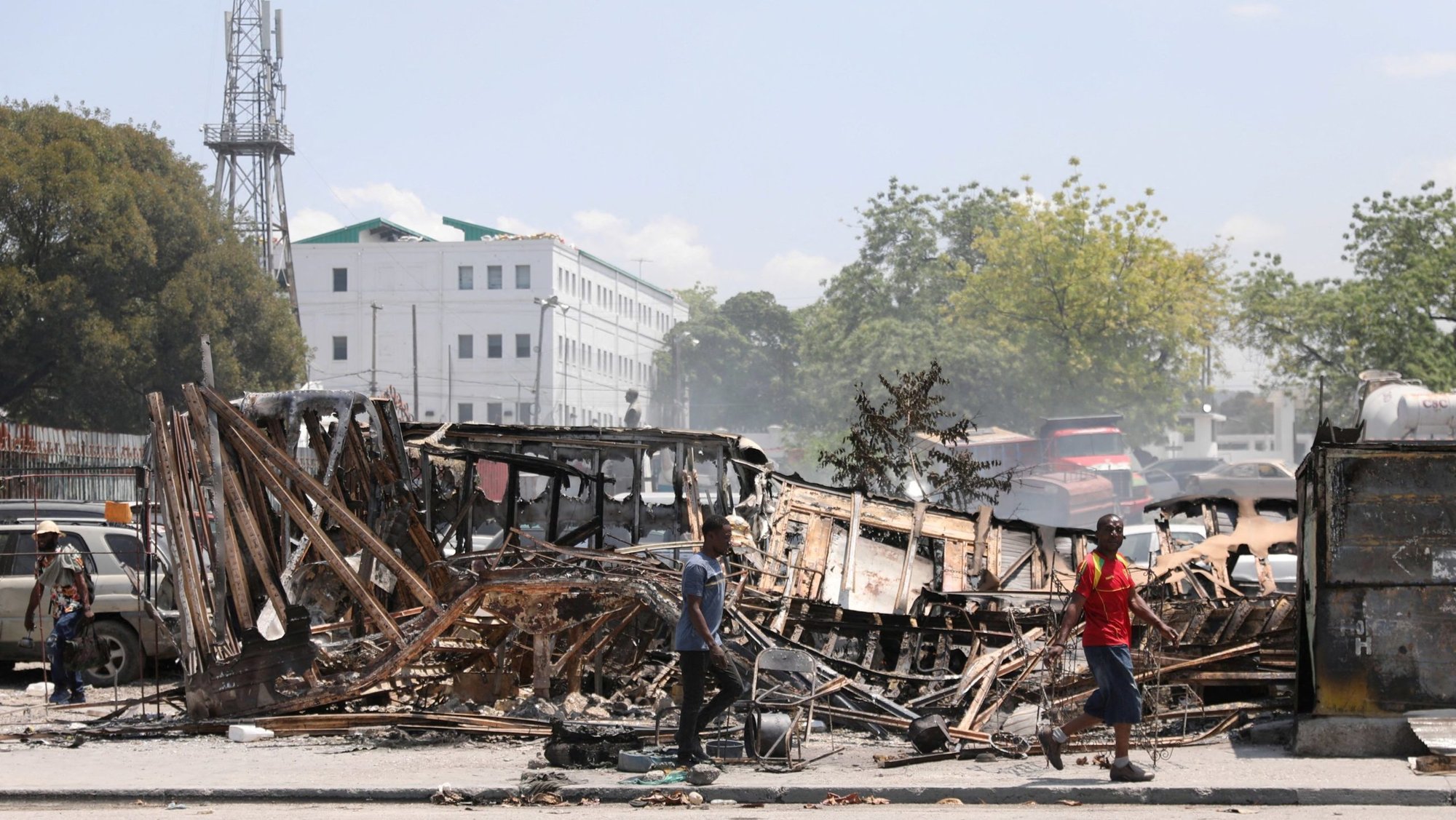 People walk past remains of vehicles near the presidential palace in Port-au-Prince, Haiti, March 25, 2024, after they were set on fire by gangs, as violence spread and armed gangs expanded their control over the capital. (OSV News photo/Ralph Tedy Erol, Reuters)