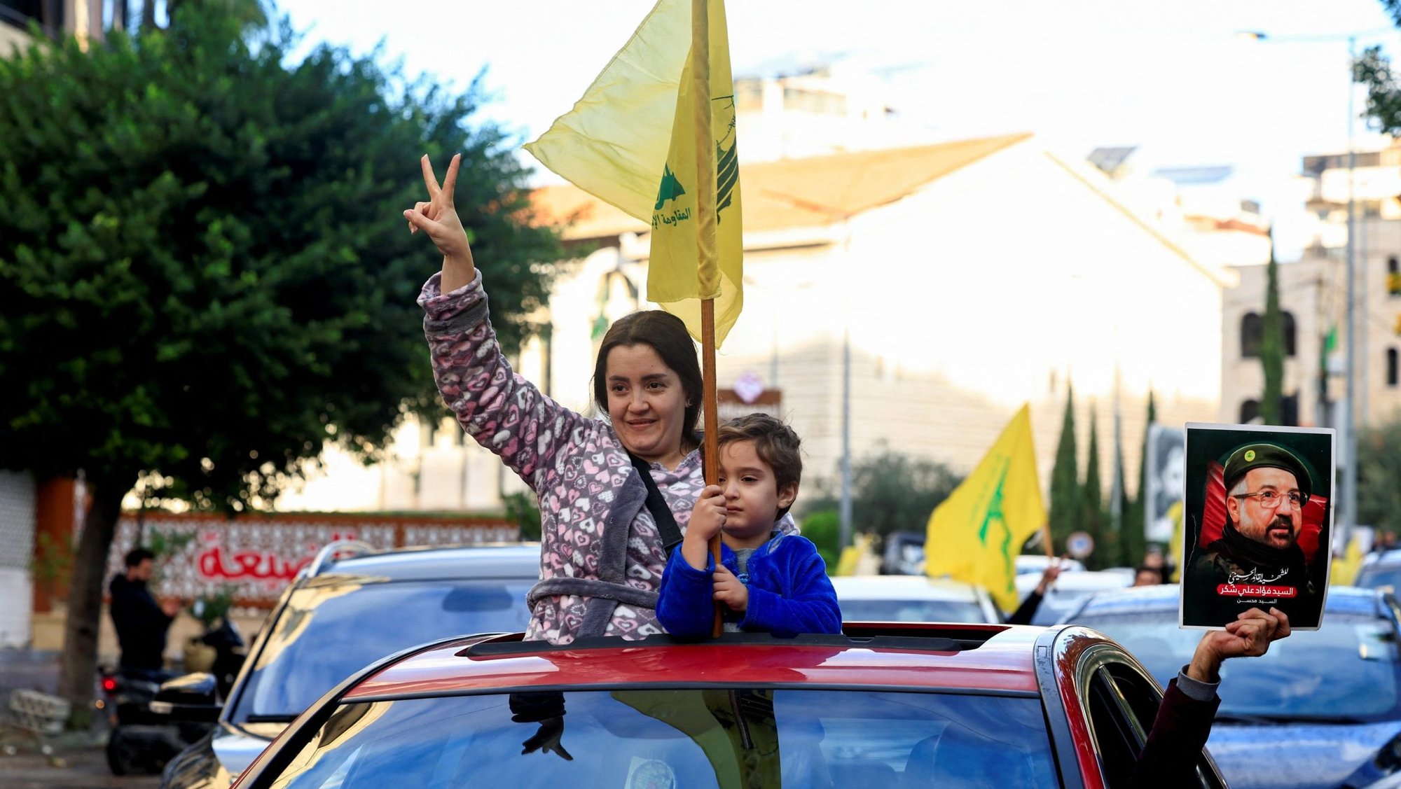 A woman accompanied by a child holding a Hezbollah flag gives a victory sign from a car at the entrance of Beirut's southern suburbs Nov. 27, 2024, after a ceasefire between Israel and Hezbollah took effect. A ceasefire between Israel and the Lebanese militant group Hezbollah appeared to be holding as residents returned toward southern Lebanon, despite warnings from the Israeli and Lebanese military that they stay away from certain areas. (OSV News photo/Thaier Al-Sudani, Reuters)
