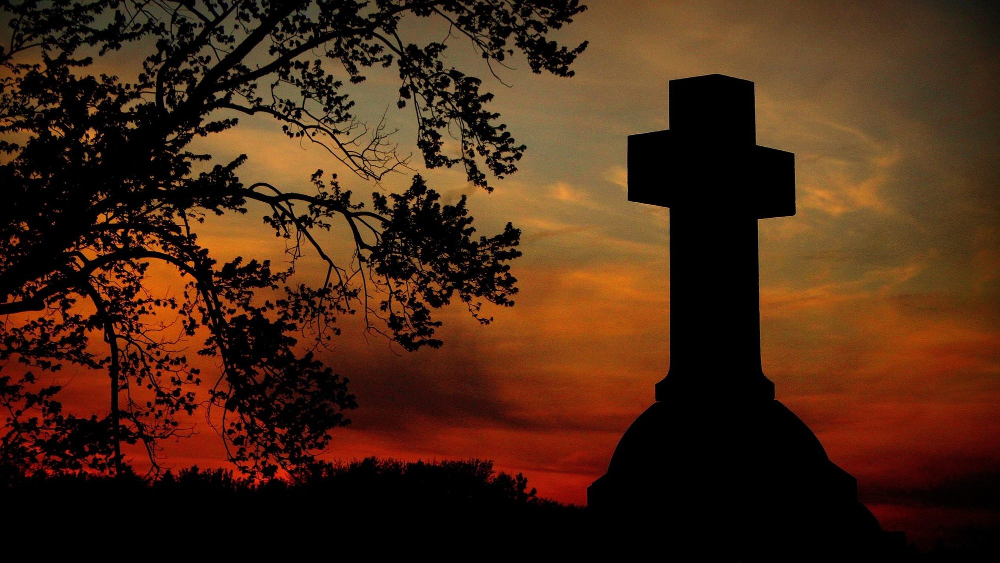 A vibrant spring sunset is pictured behind a cross grave marker at St. Patrick Catholic Cemetery in Neenah, Wis., May 15, 2019. (OSV News file photo/Brad Birkholz)