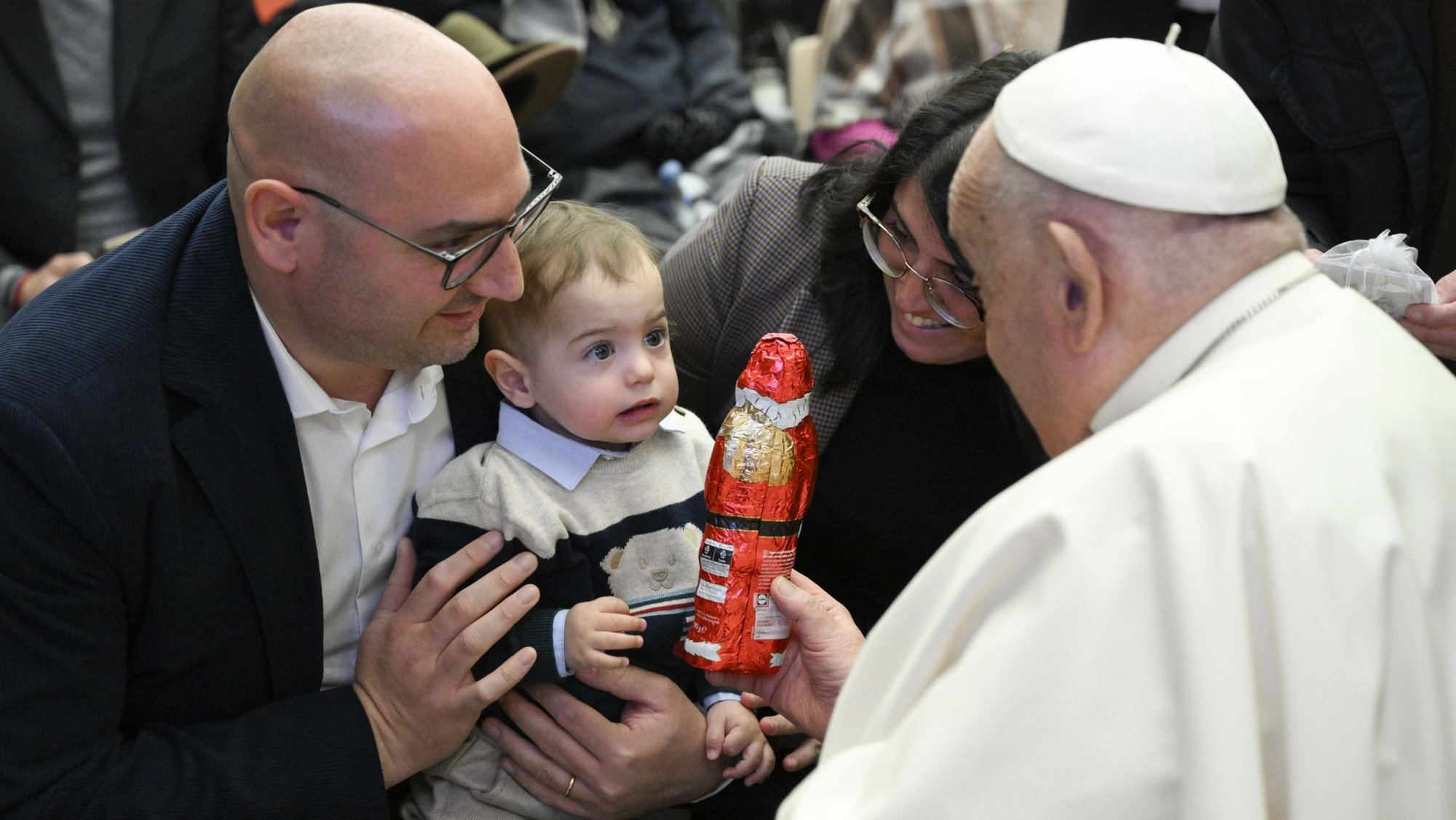 Pope Francis gives a child a large chocolate Santa after his weekly general audience in the Paul VI Audience Hall at the Vatican Dec. 18, 2024. (CNS photo/Vatican Media)