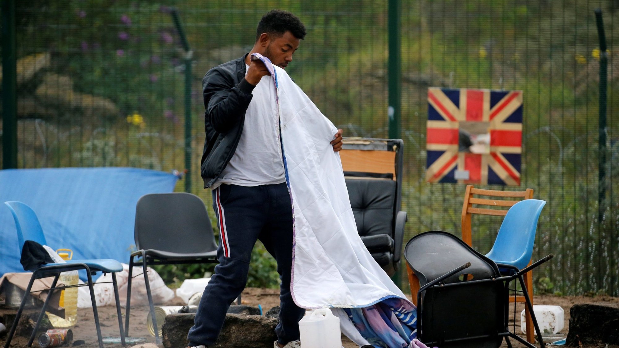 A migrant packs his belongings as French police officers dismantle a makeshift shelter camp in Calais July 10, 2020. (CNS photo/Pascal Rossignol, Reuters)