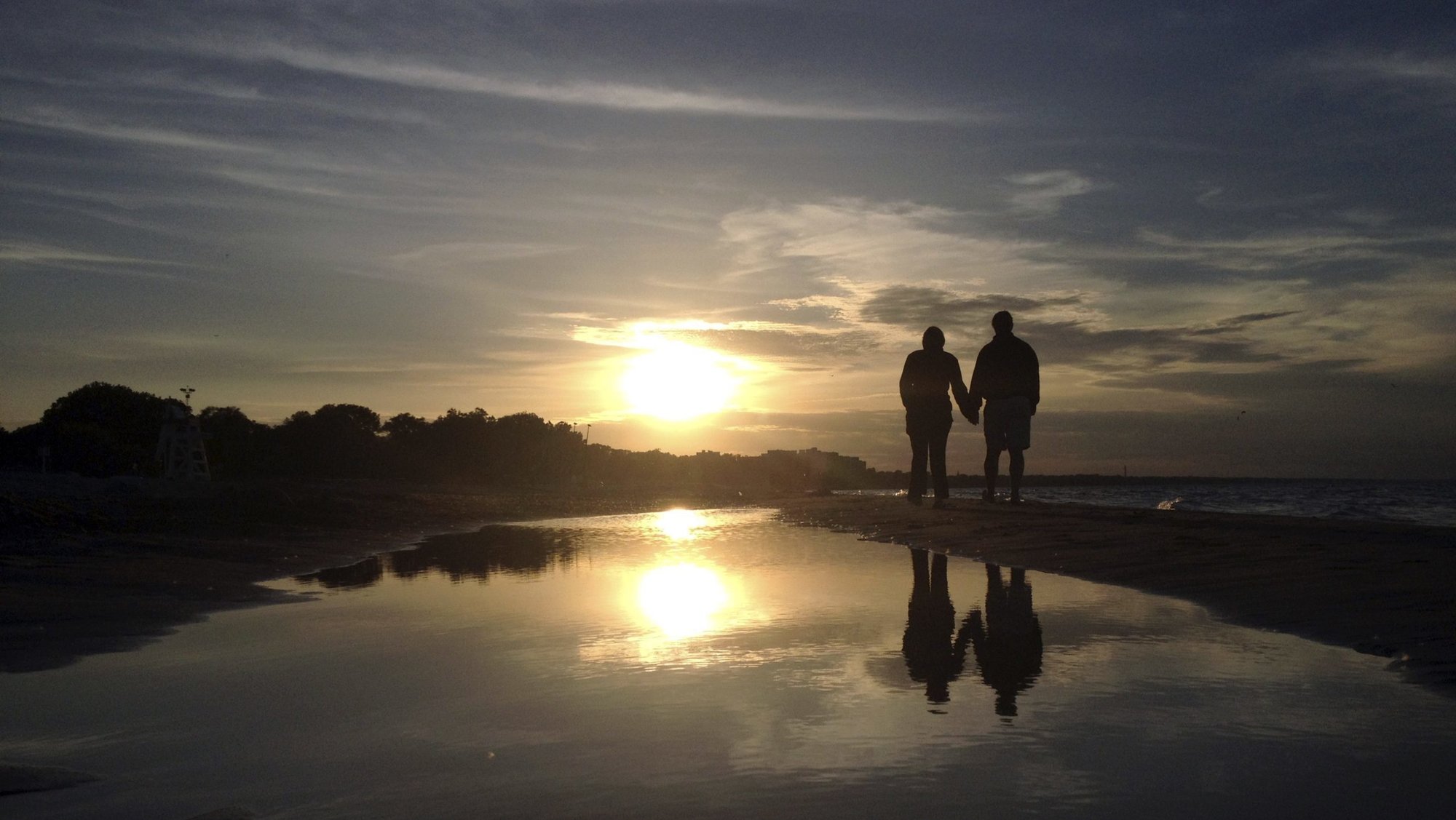 A couple is pictured in a file photo walking along Gillson Beach holding hands as the sun sets in Wilmette, Ill. According to the U.S. Census Bureau, in 2023, 46.4% of American adults -- 117.6 million -- were single. That figure included those who were divorced, widowed or never married. (OSV News photo/Jim Young, Reuters)