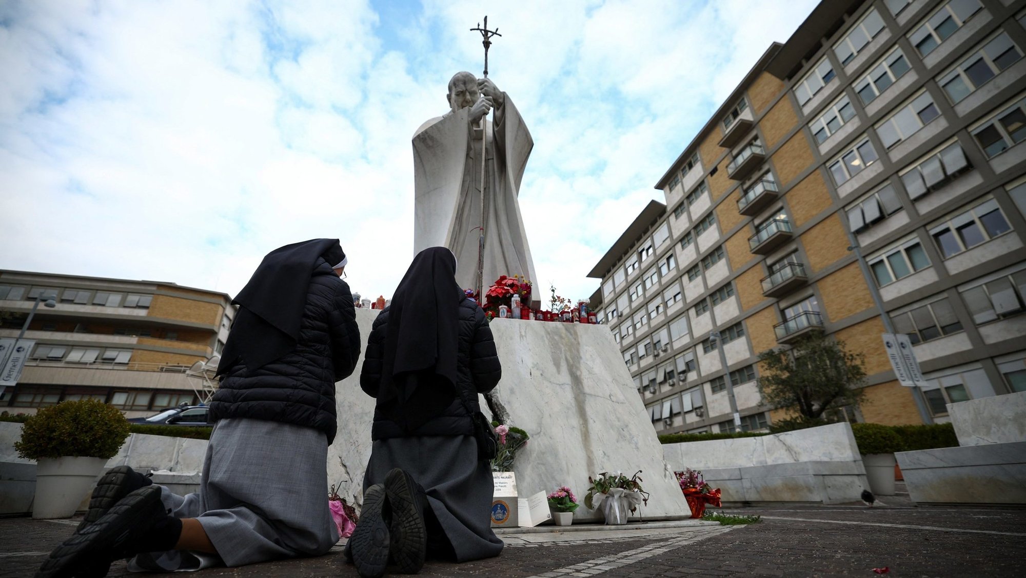 Nuns pray next to the statue of St. John Paul II outside Rome's Gemelli Hospital Feb. 20, 2025, where Pope Francis is admitted for treatment for a respiratory infection. The Vatican press office said early Feb. 20 that the pope had a peaceful night, "got up and had breakfast in an armchair." (OSV News photo/Guglielmo Mangiapane, Reuters)