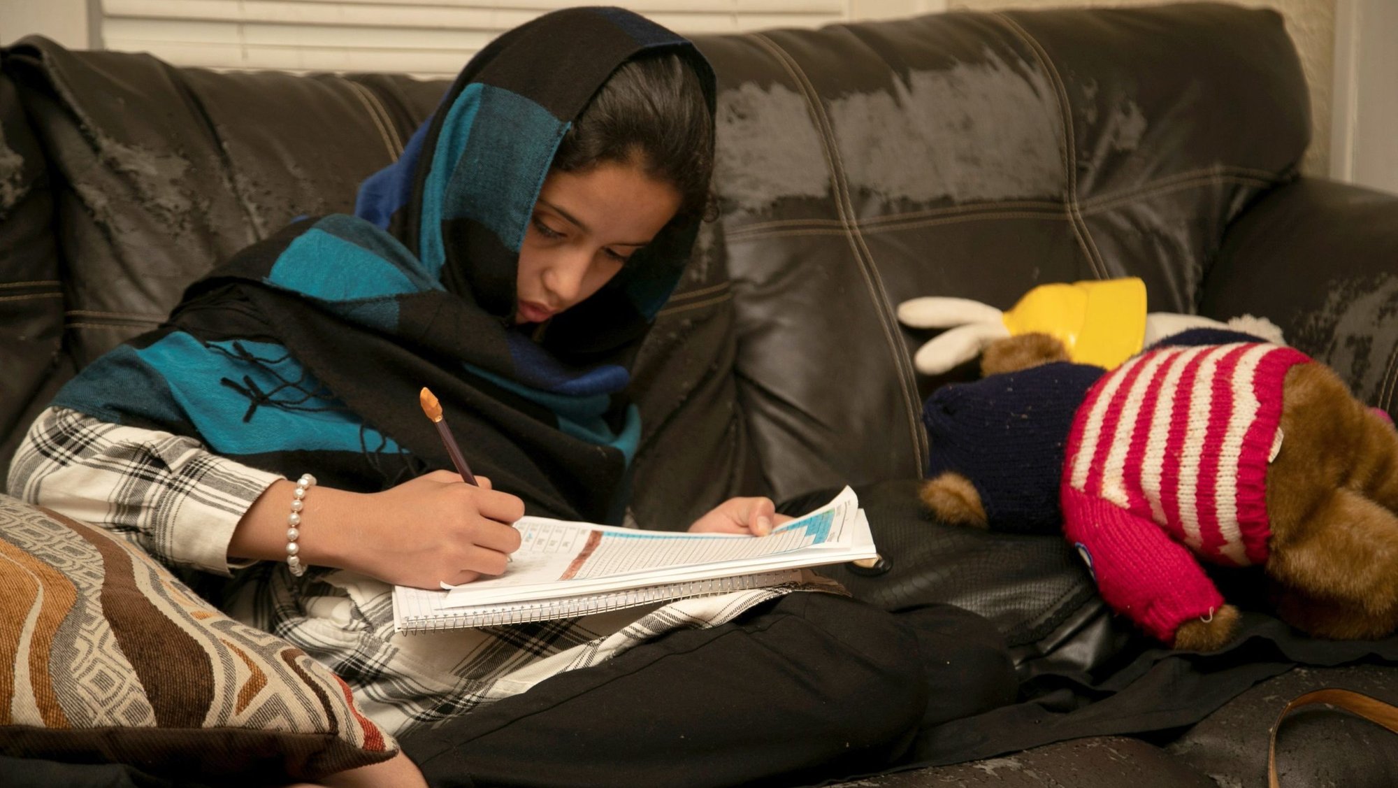 A young woman works on her homework at home in Bowling Green, Ky., Nov. 27, 2021. The Zadran family, Afghan refugees fleeing the Taliban, came to Bowling Green after a spell at a New Mexico military base. The U.S. Conference of Catholic Bishops said it would not renew its cooperative agreements with the federal government related to children’s services and refugee support after its longstanding partnerships with the federal government in those areas became "untenable." (OSV News photo/Amira Karaoud, Reuters)
