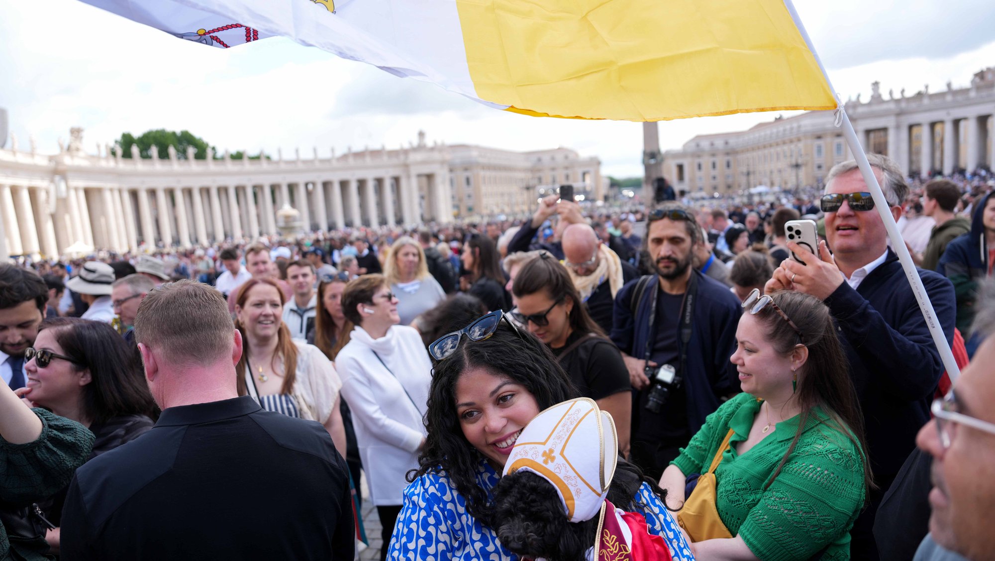 Marilis Pineiro holds her dog, Romeo, dressed as a pope, as people gather in St. Peter’s Square at the Vatican May 8, 2025, awaiting smoke from the Sistine Chapel chimney during the morning session on the second day of the conclave to elect a new pope. (CNS/Lola Gomez)