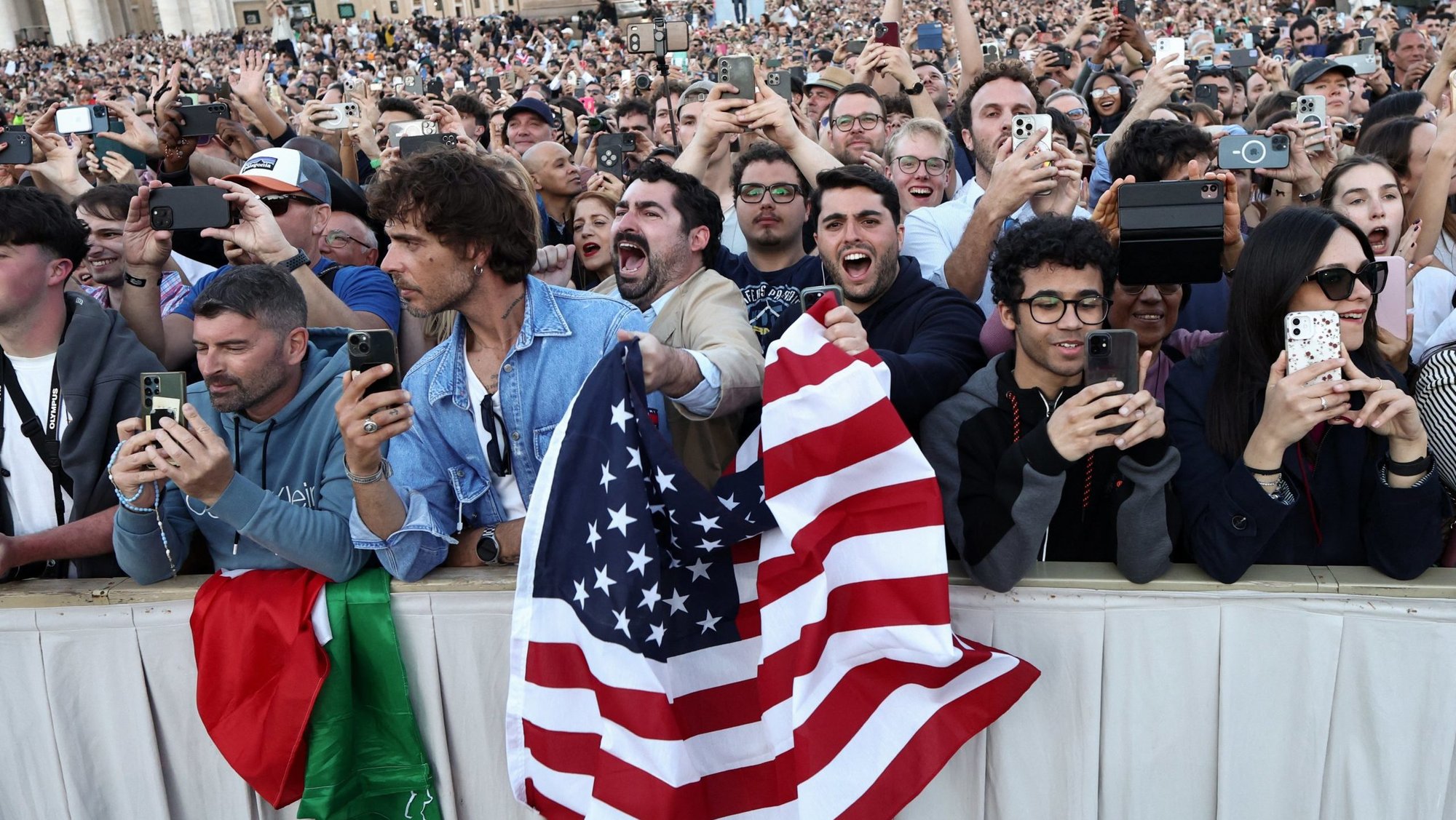 Men wave a U.S. flag as Cardinal Robert Francis Prevost, who has chosen the papal name Leo XIV, appears on the central balcony of St. Peter's Basilica at the Vatican May 8, 2025, following his election during the conclave. He is the first American pope in history. (OSV News photo/Eloisa Lopez, Reuters)
