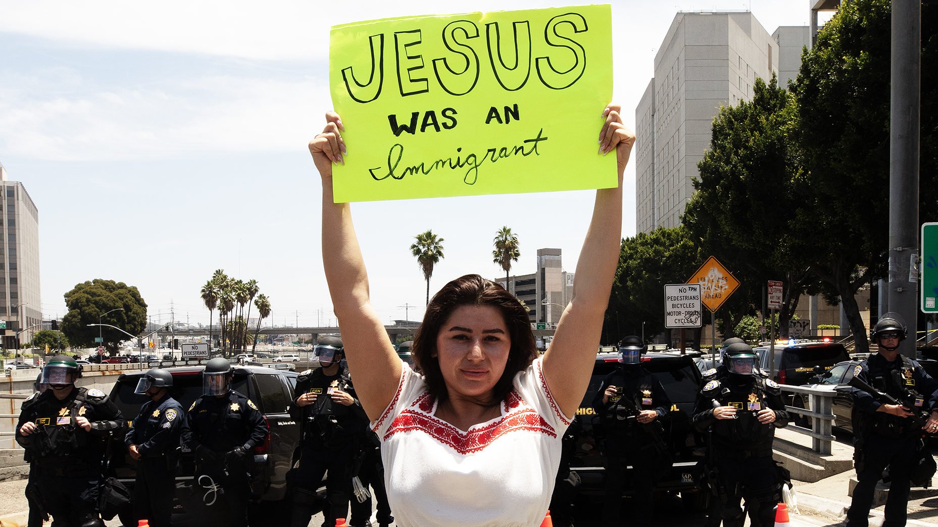 A woman holds a sign in front of a freeway offramp closed during pro-immigrant protests in downtown Los Angeles June 14, 2025. (Victor Alemán)